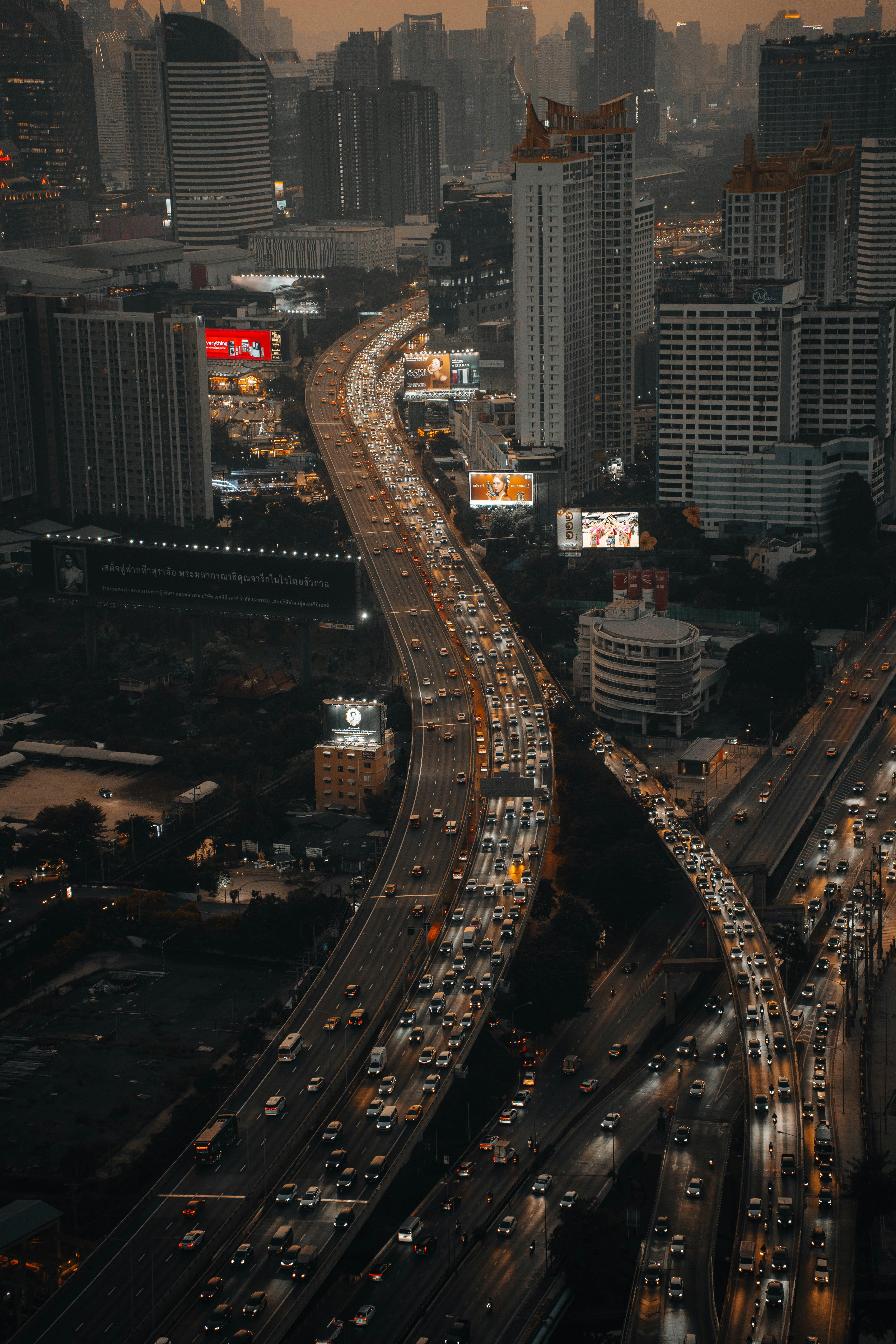 Aerial view of a busy highway in a city with tall buildings and traffic at dusk.