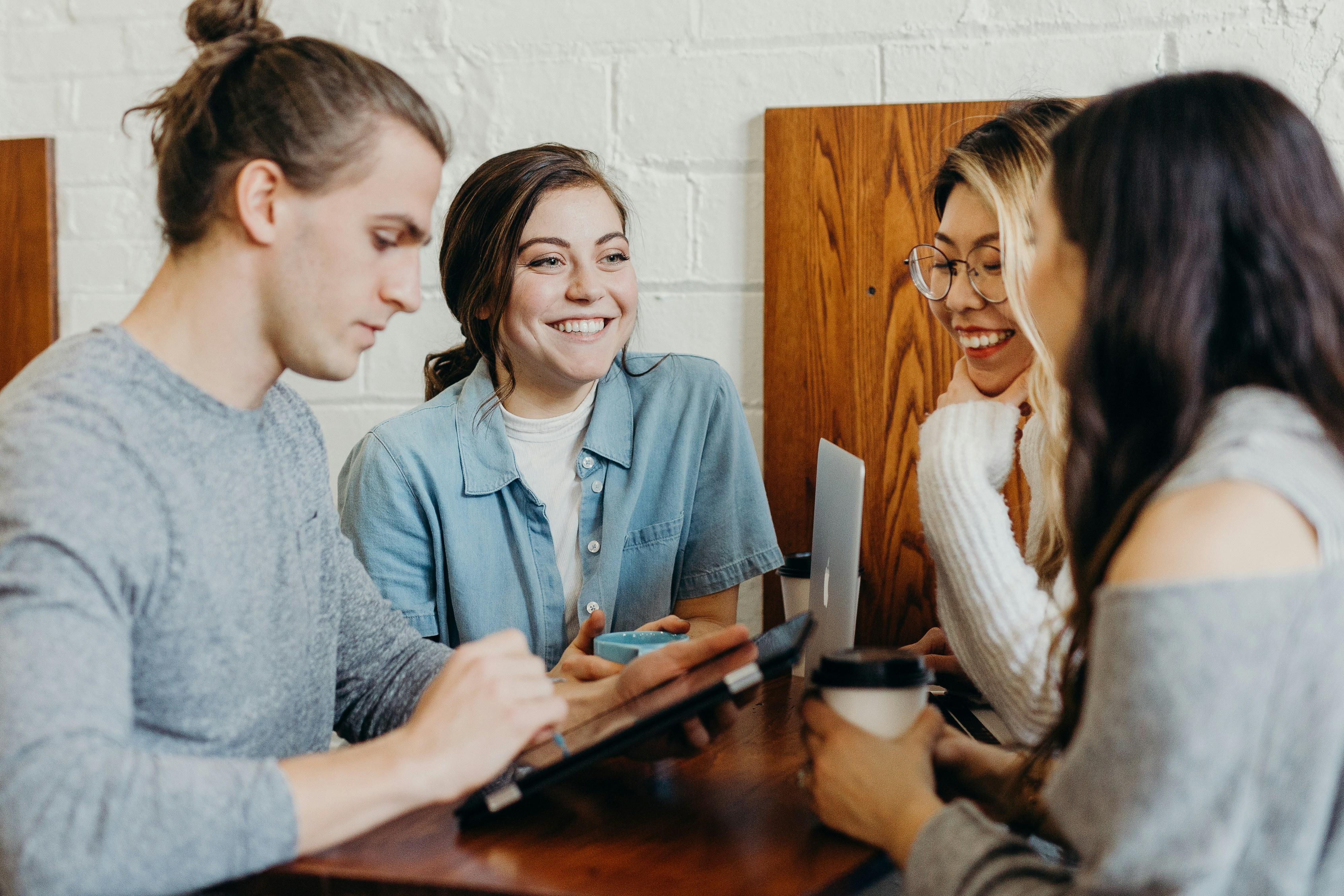 Group of four young adults having a meeting at a cafe table.