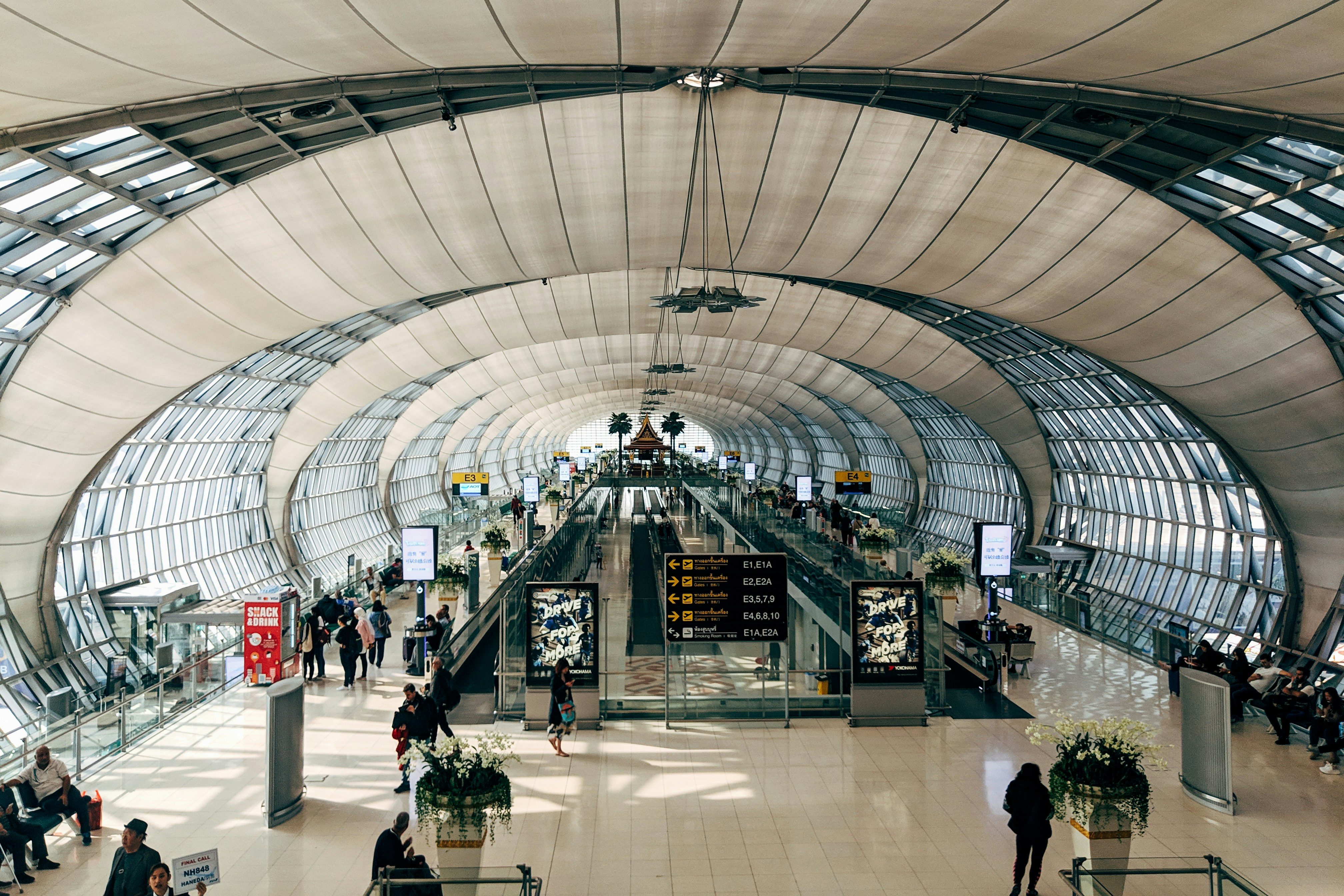 Interior view of a modern airport terminal with travelers and moving walkways
