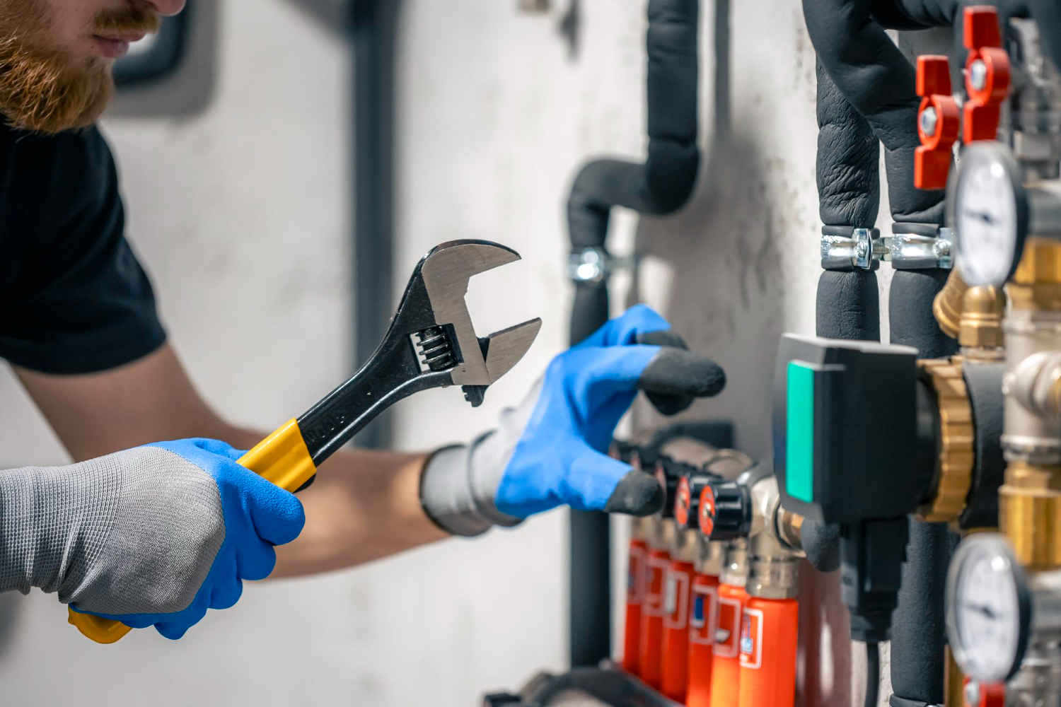 Plumber using a wrench to adjust pipes and valves in a mechanical room