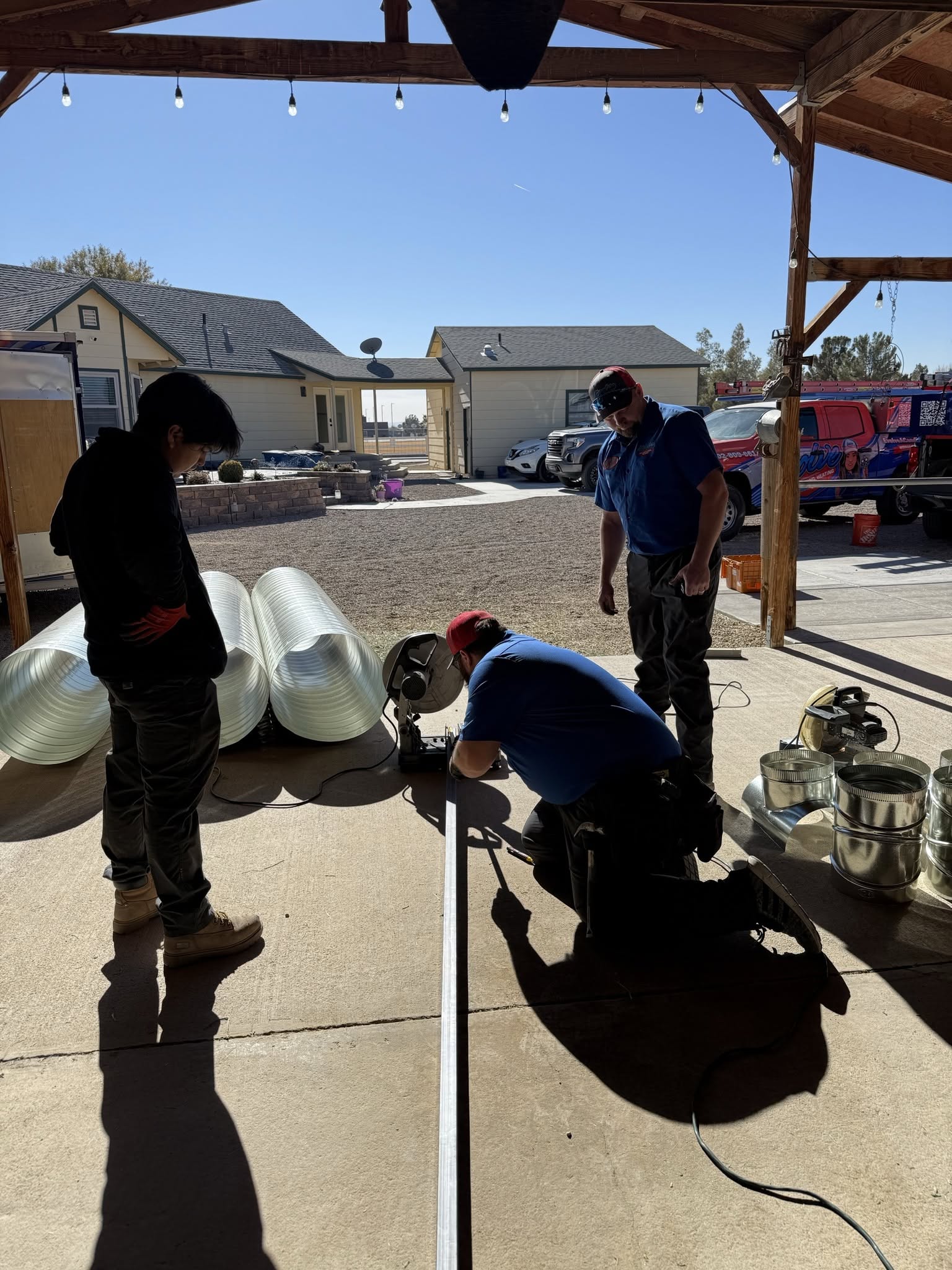 Technicians working on HVAC installation in a residential area with ductwork and tools.