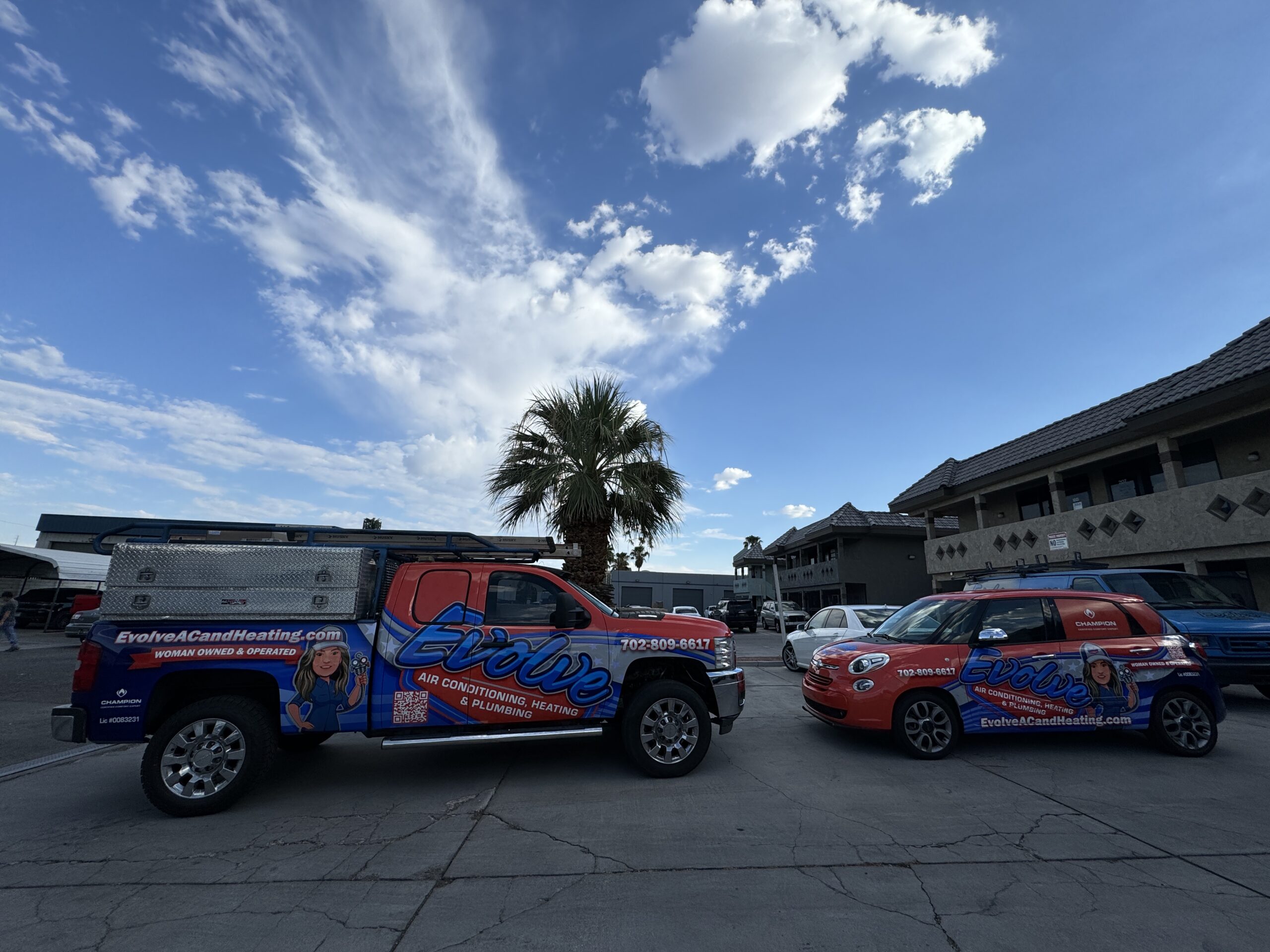 Evolve Air Conditioning and Heating service vehicles parked outside a building under a blue sky.