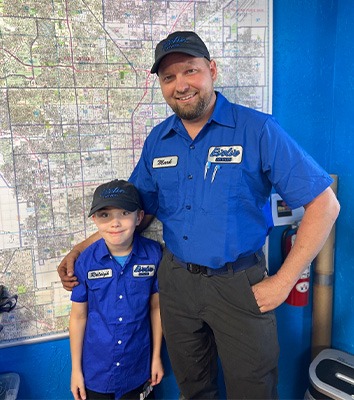 Adult and child in matching blue uniforms standing in front of a large map.