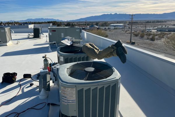 Technician working on rooftop HVAC units with mountains in the background