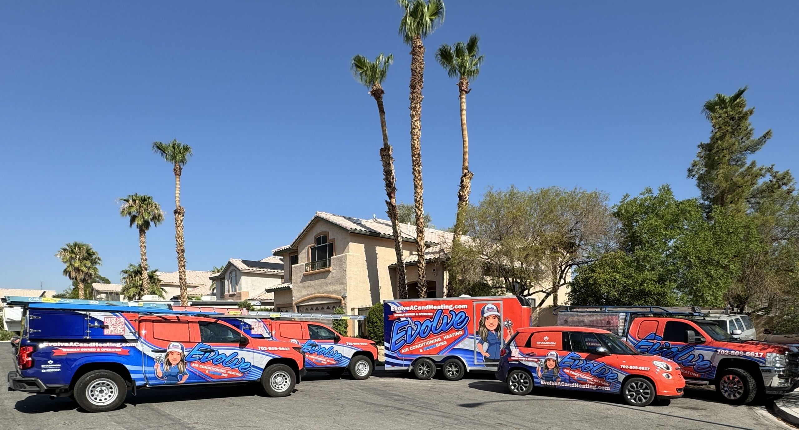Evolve Air Conditioning, Heating & Plumbing service vehicles parked in front of a residential home.