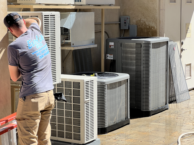 Technician servicing outdoor air conditioning units on a sunny day