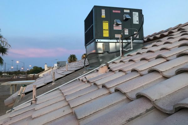 Rooftop HVAC unit installed on a residential home at sunset.