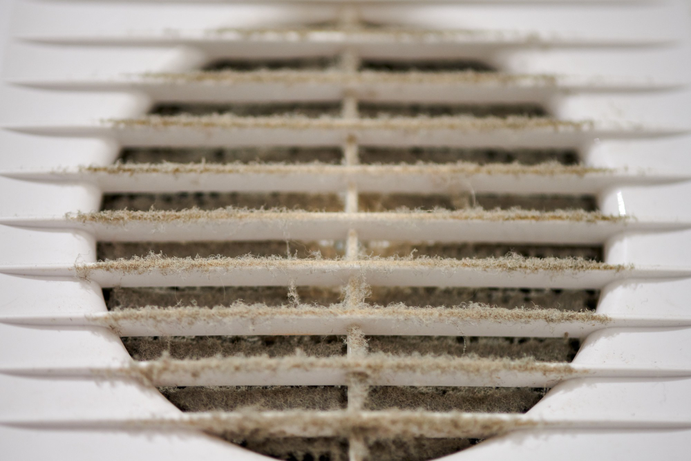 Close-up of a dusty air vent grille with visible dirt accumulation