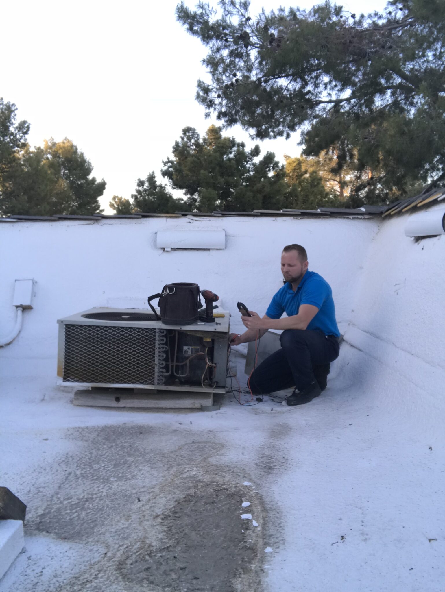 Technician inspecting an air conditioning unit on a rooftop.