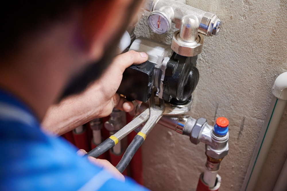 Plumber using pliers to adjust a valve on a heating system