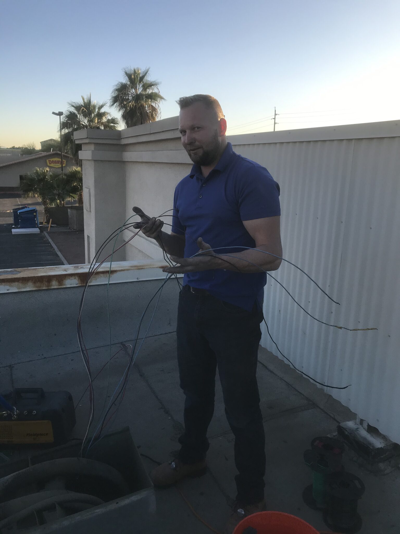 Technician holding wires on a rooftop during HVAC maintenance