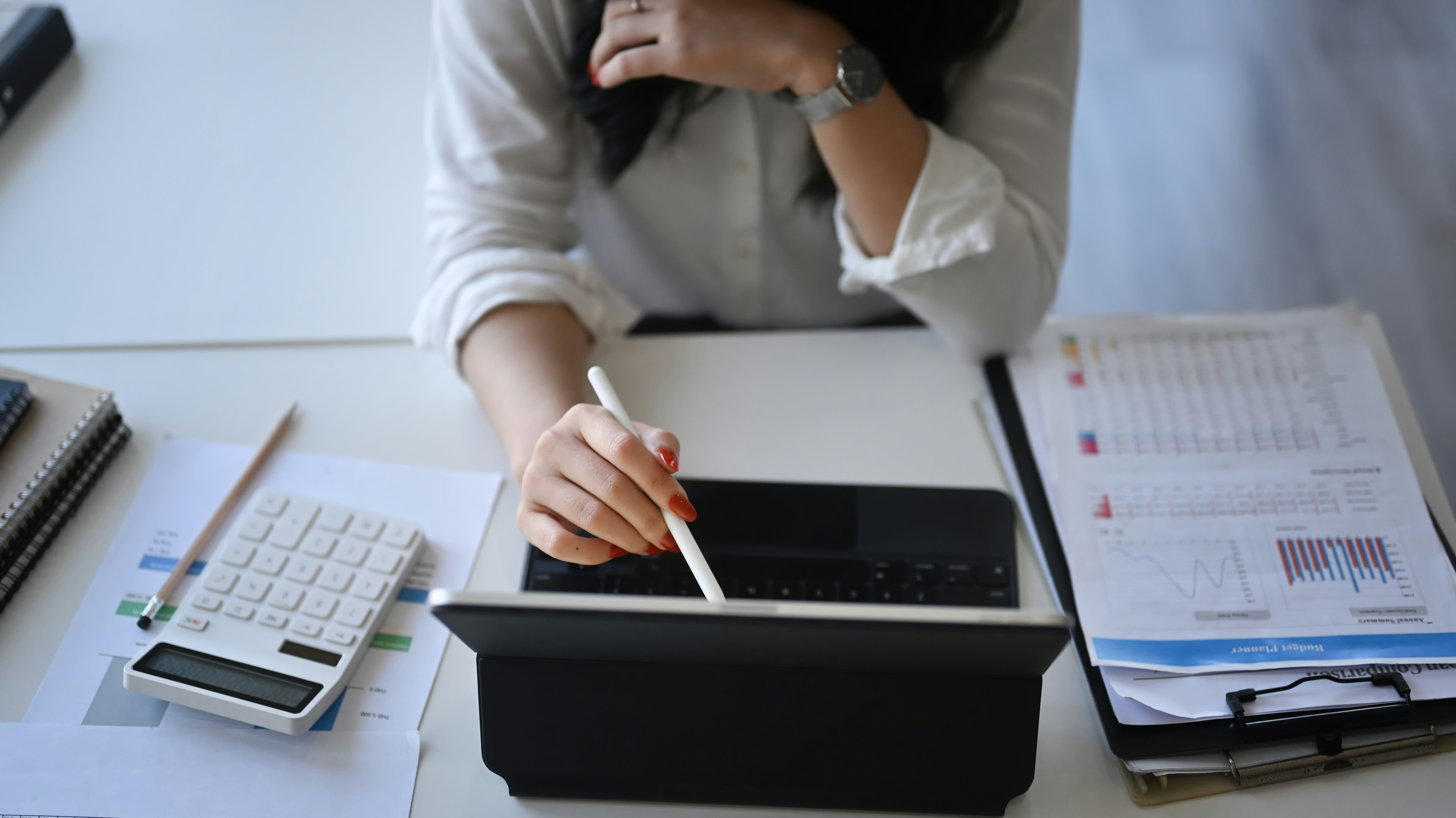 Two people discussing documents at a table with a laptop in a bright office