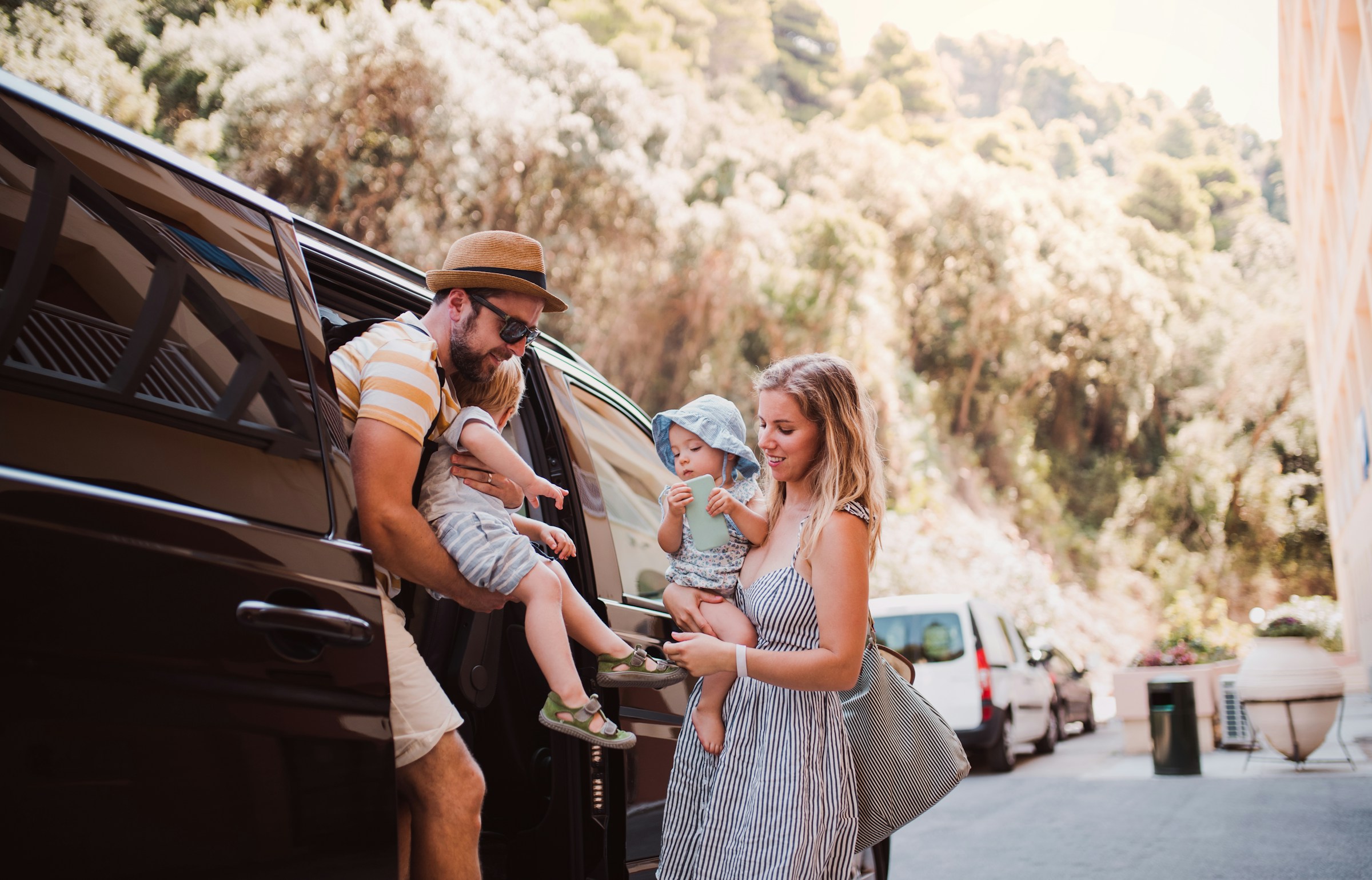 Family with two children getting out of a car on a sunny day