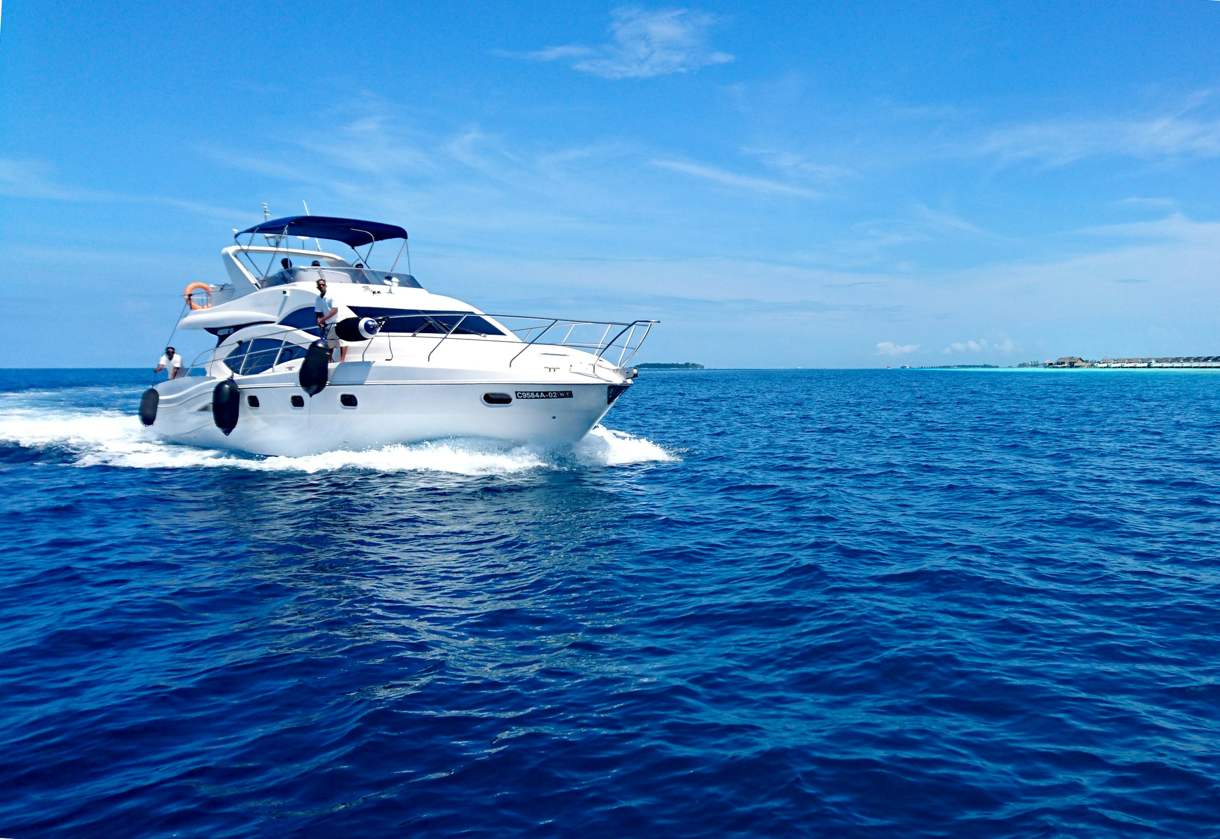 White yacht cruising on a clear blue ocean under a bright sky