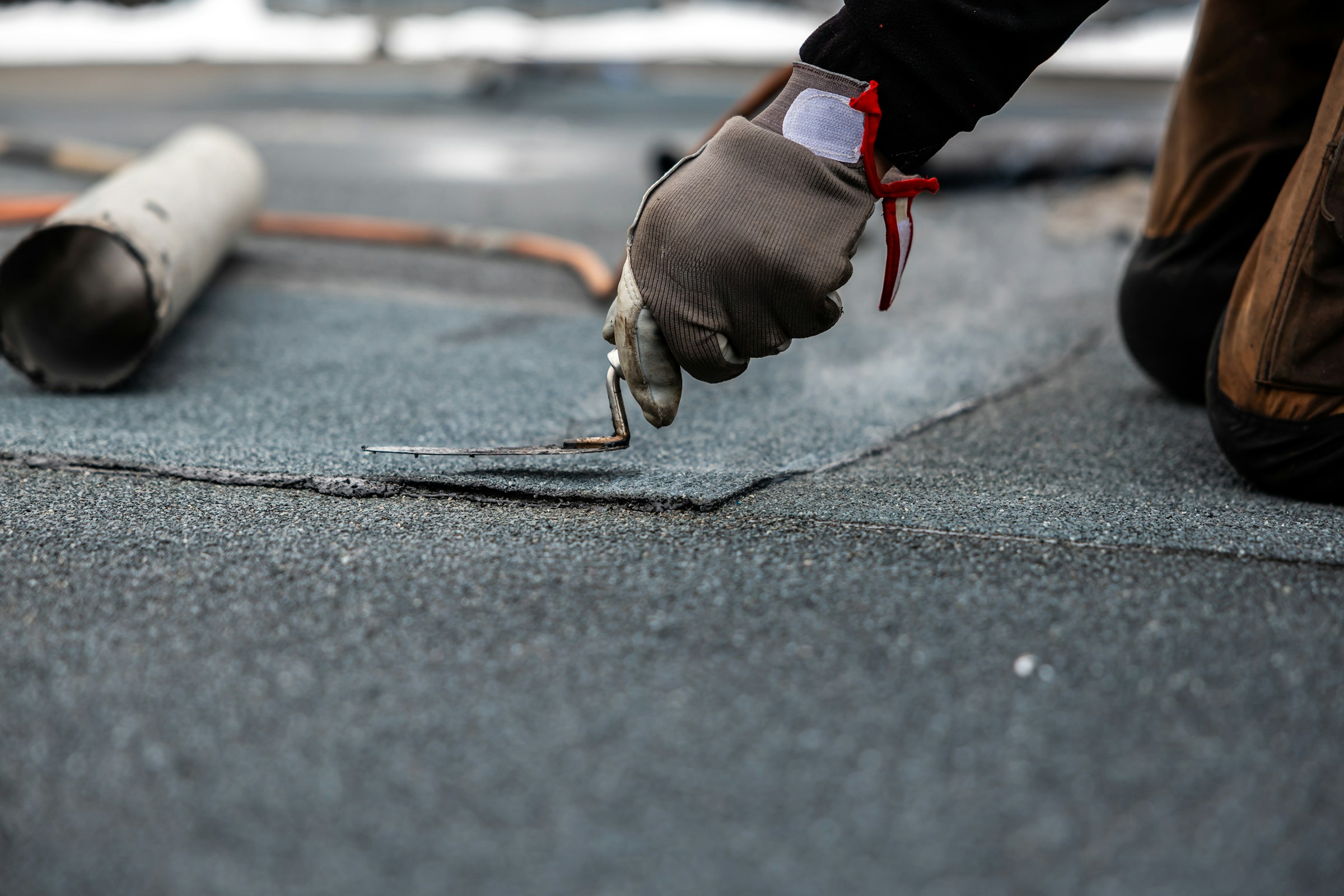 Close-up of a worker applying roofing material with a trowel
