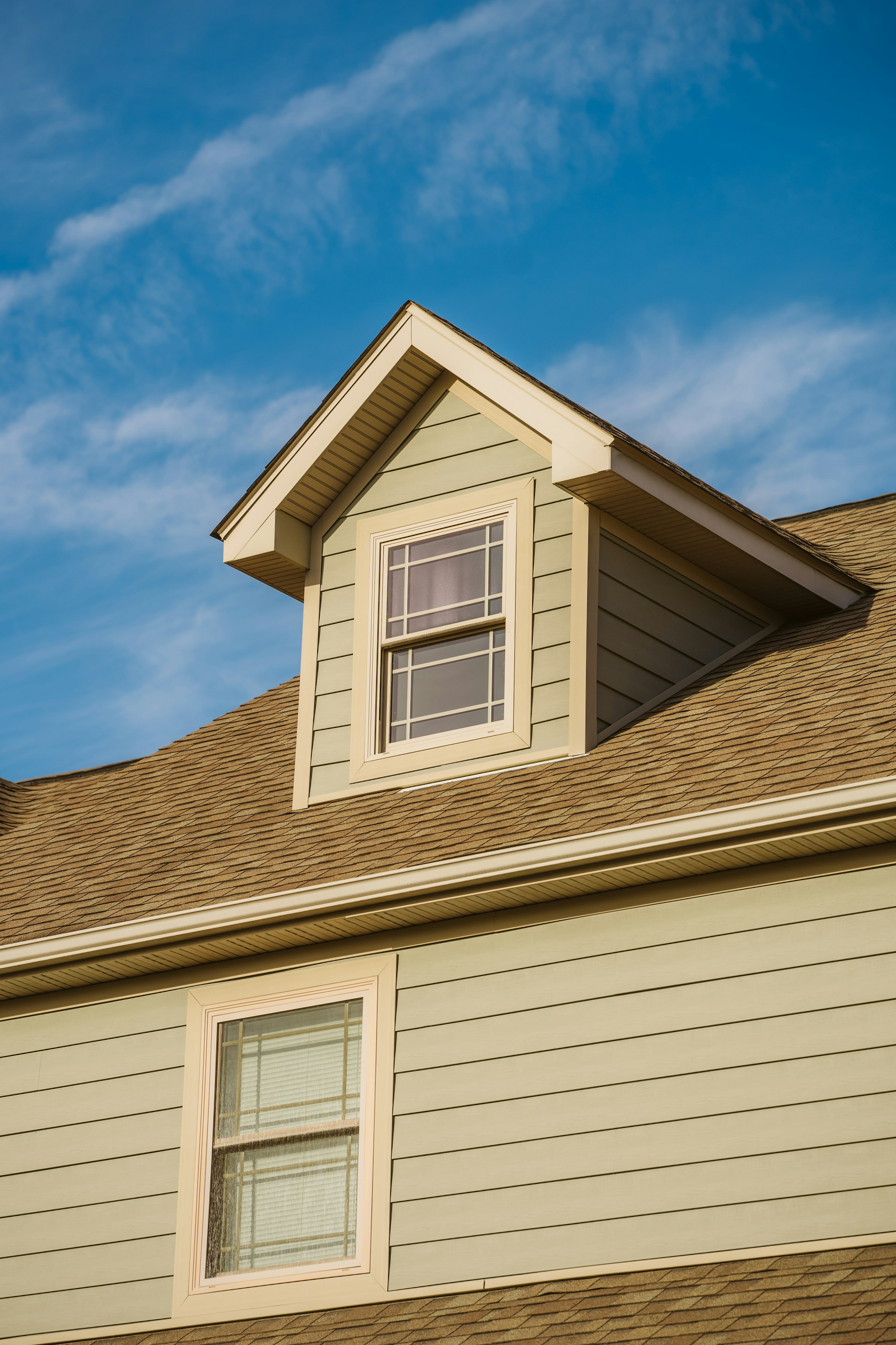 Close-up of a house with green siding and a dormer window