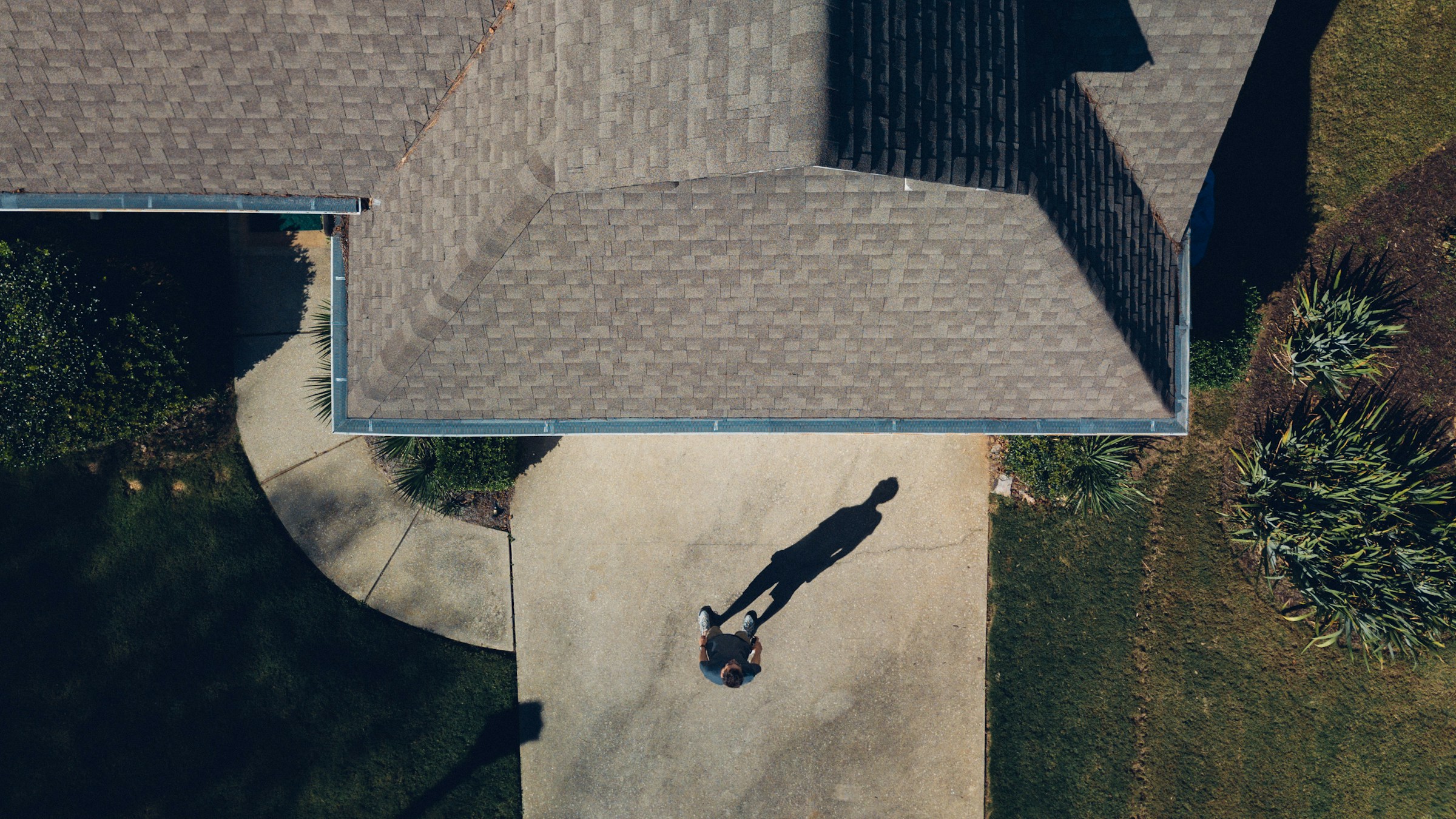 Aerial view of a house roof with a person standing on the driveway
