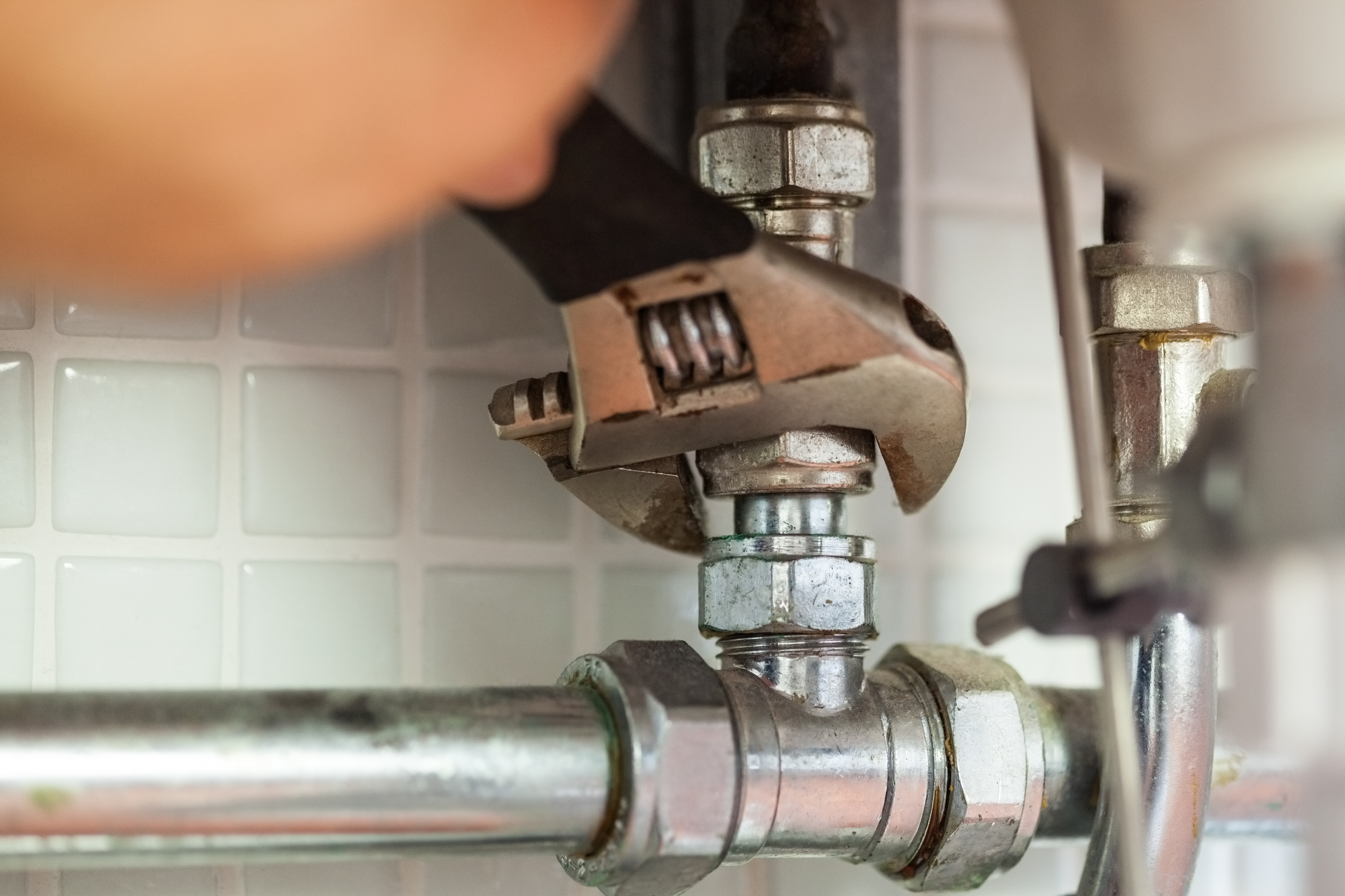 Outdoor plumbing pipes and valves with blue handles beside a wall