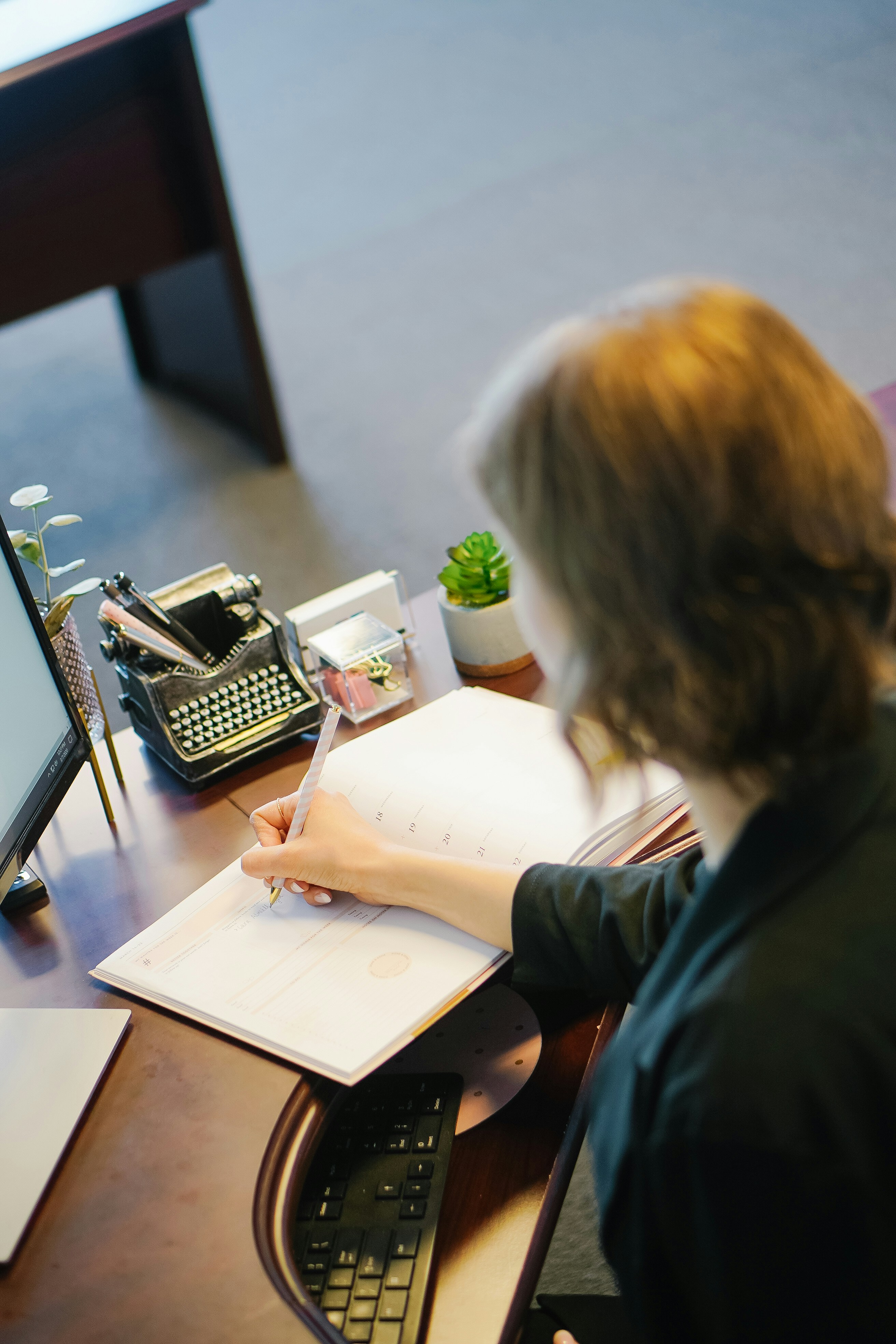 Wedding rings on a divorce document as a person signs it with a pen.