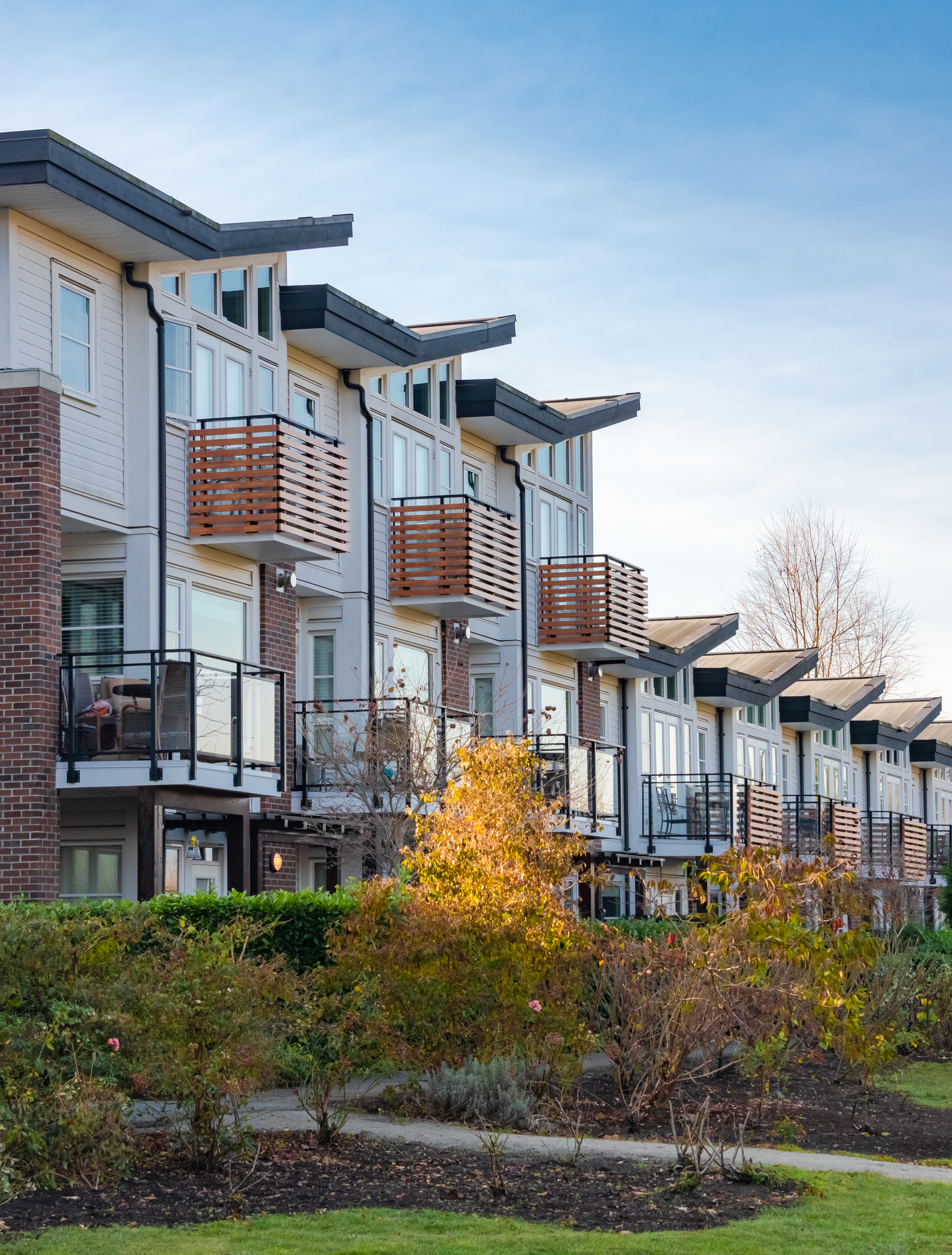 Row of modern townhouses with balconies and landscaped front yards
