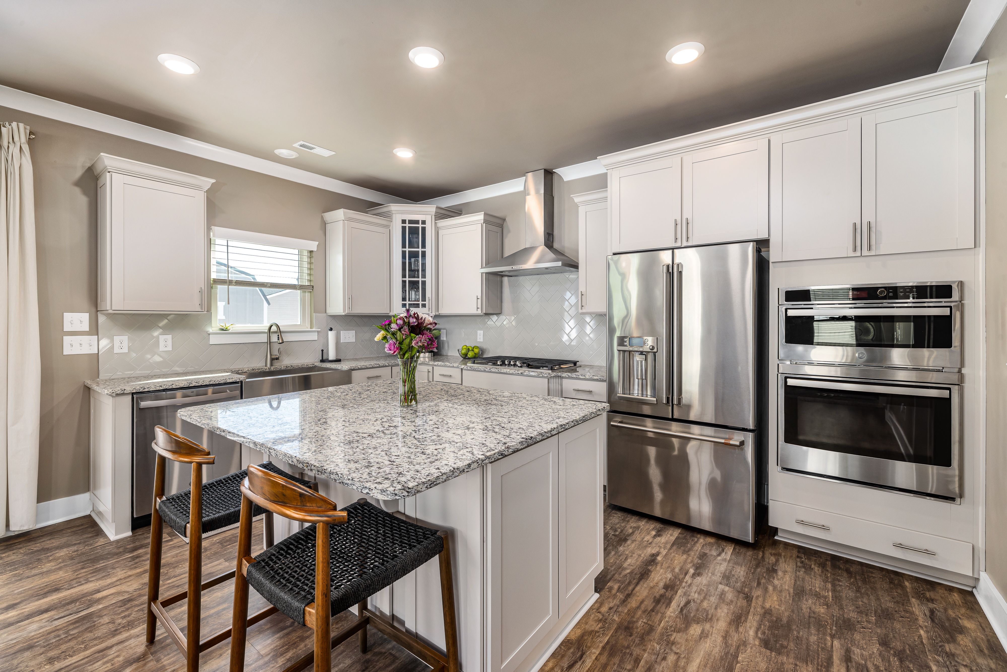 Modern kitchen with white cabinets, stainless steel appliances, and a granite island.