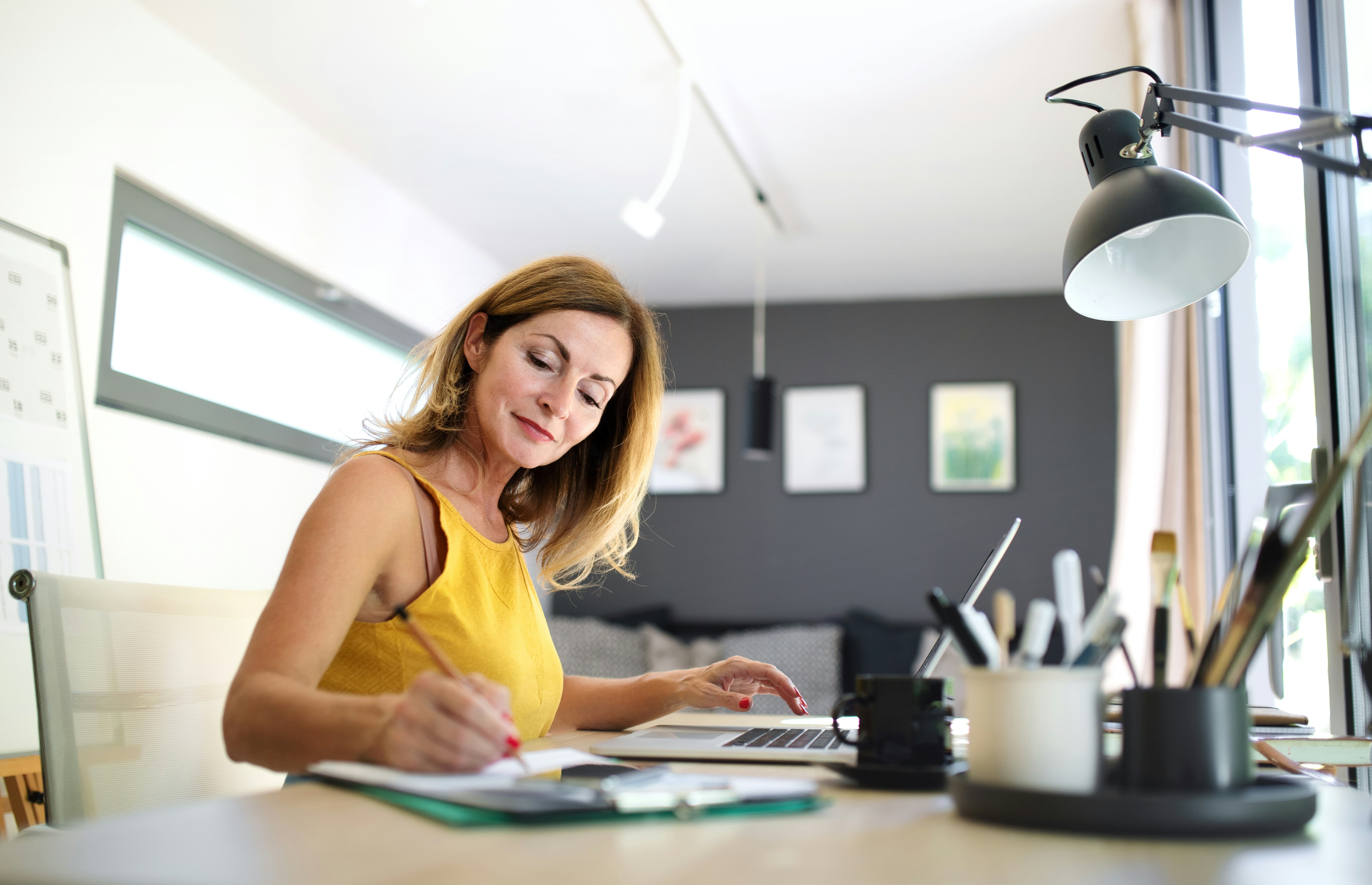 Woman working at a desk with a laptop and documents in a modern office.