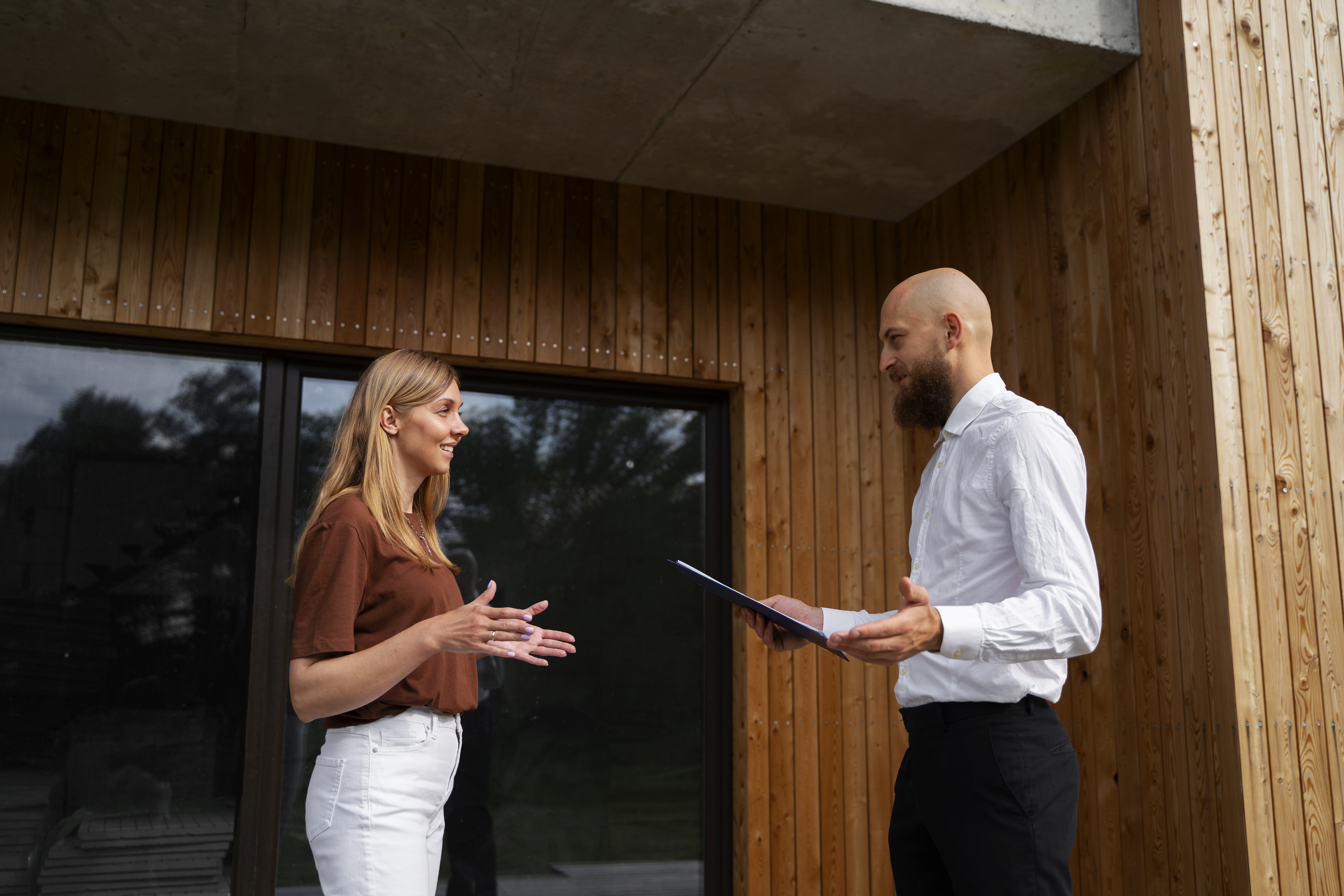 Two people discussing in front of a modern wooden building