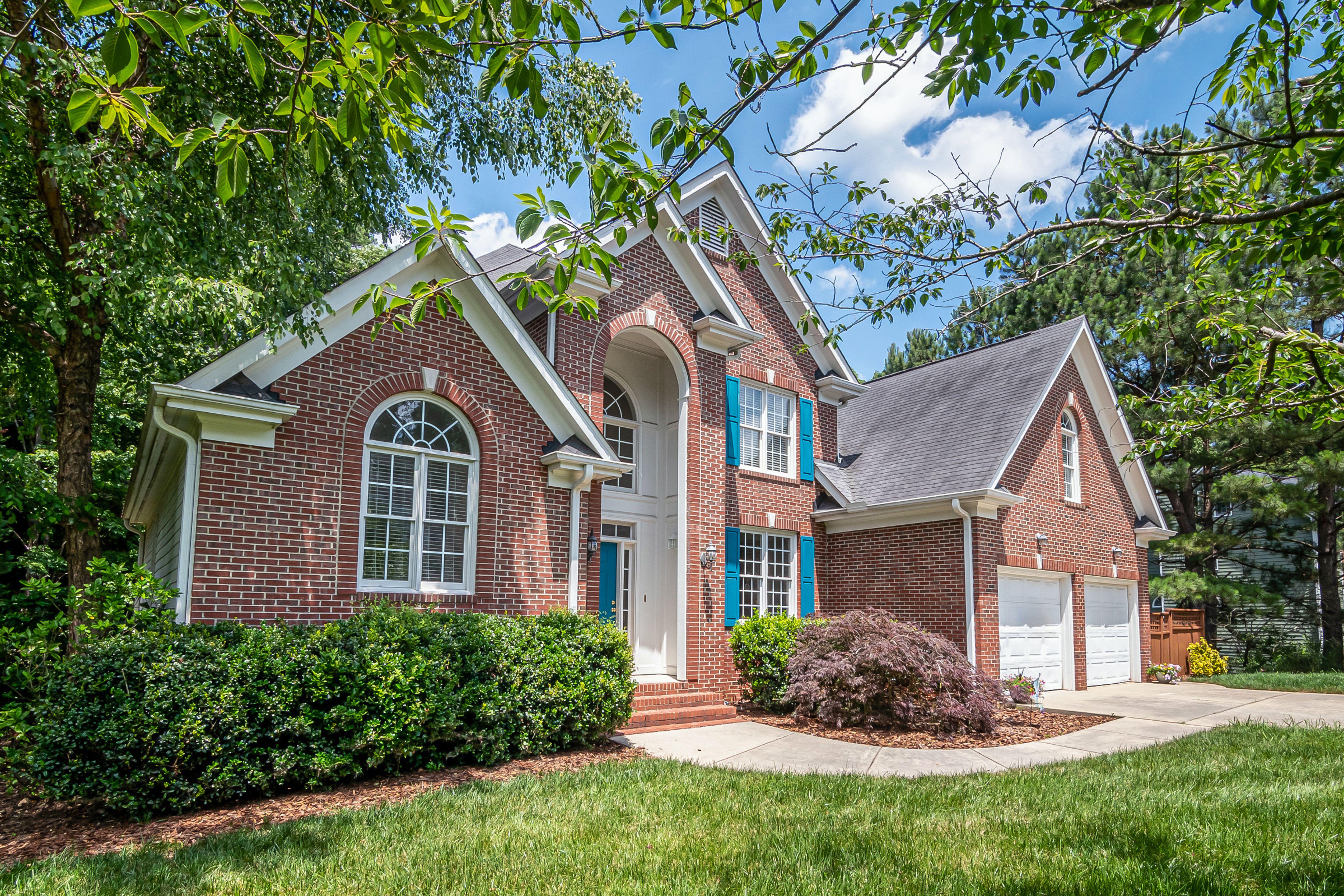 Brick house with arched windows and a two-car garage surrounded by greenery