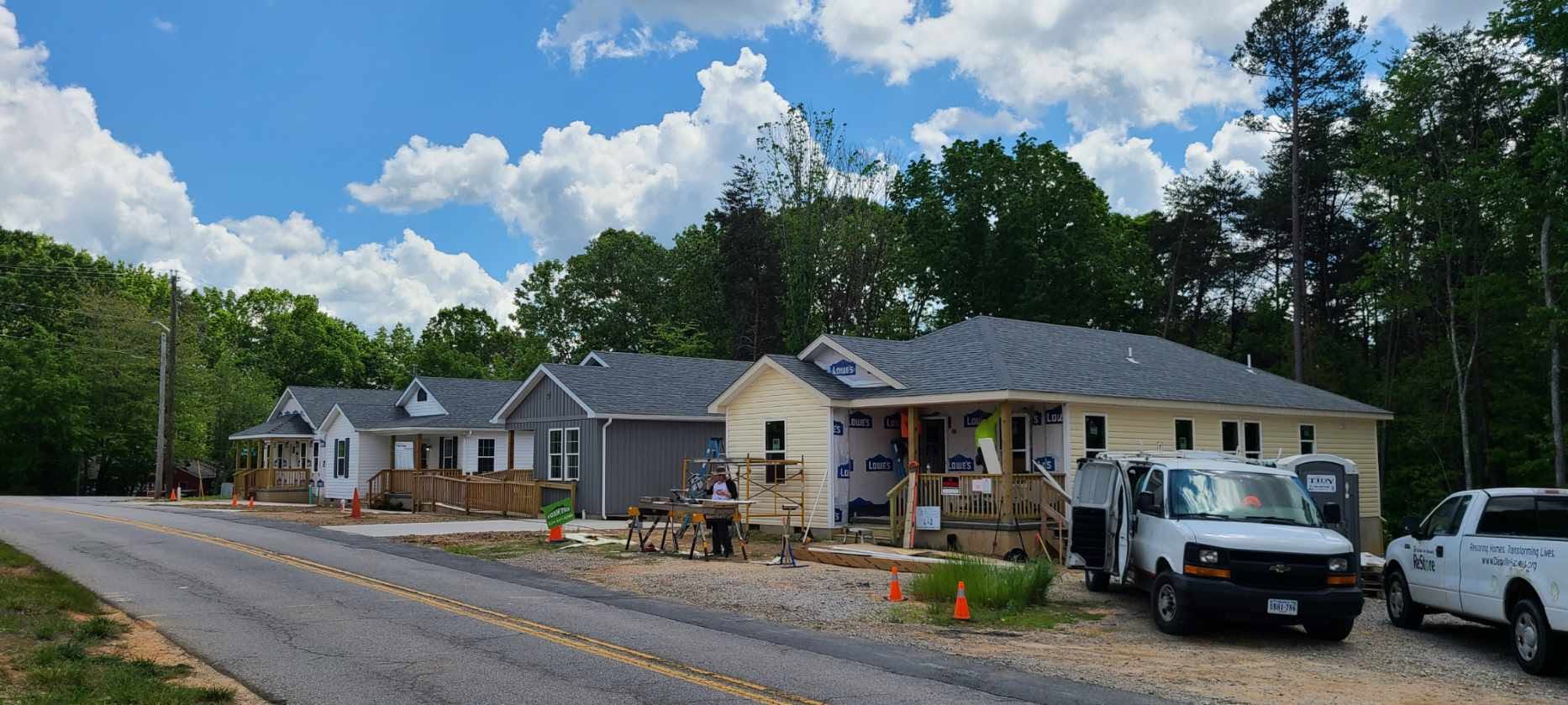 Four construction workers standing inside a framed wooden house under construction.