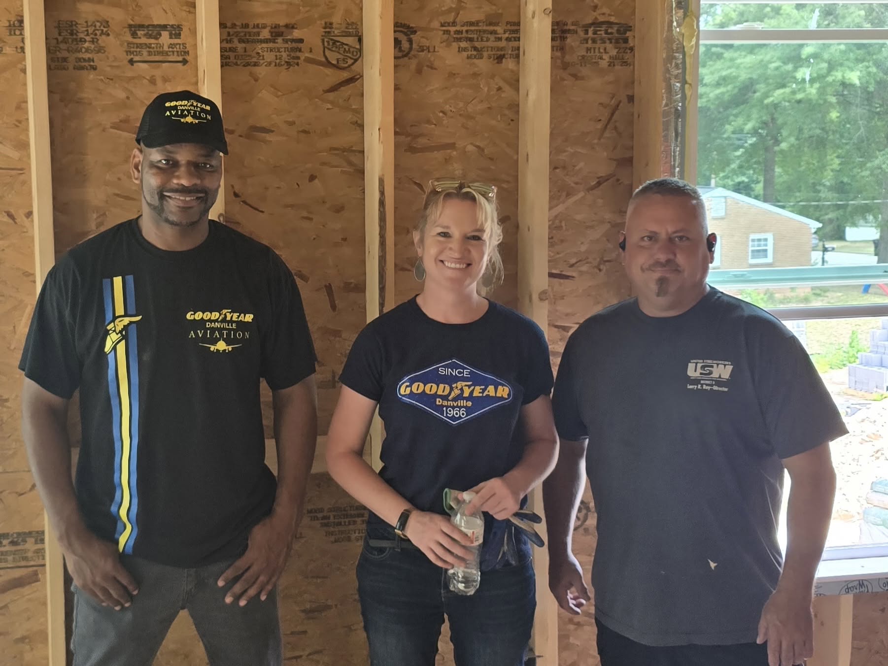 Four construction workers standing inside a framed wooden house under construction.