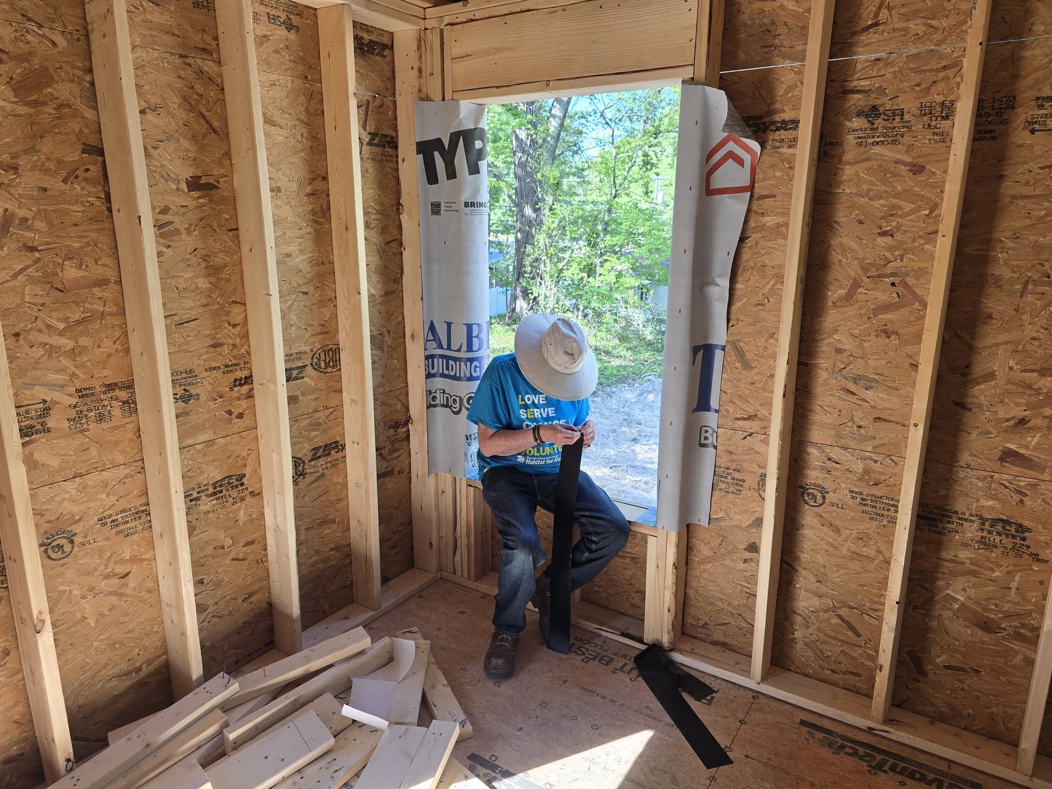 Four construction workers standing inside a framed wooden house under construction.