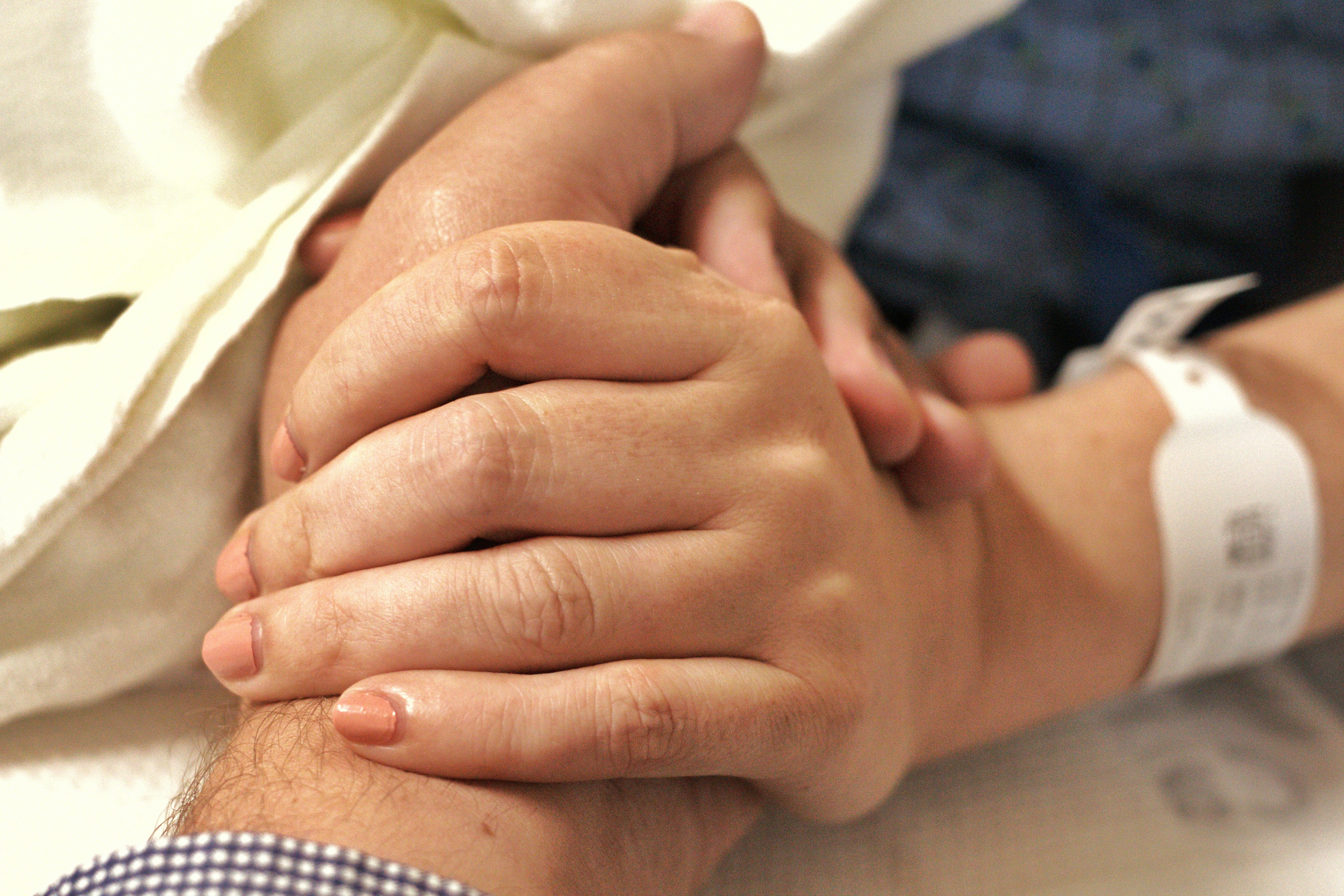 Hands stacked together with a healthcare provider in the background.