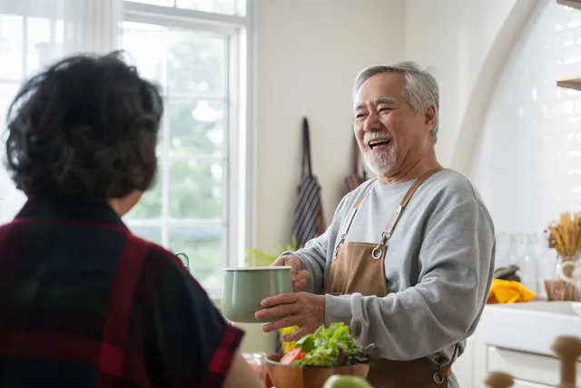 Hands stacked together with a healthcare provider in the background.