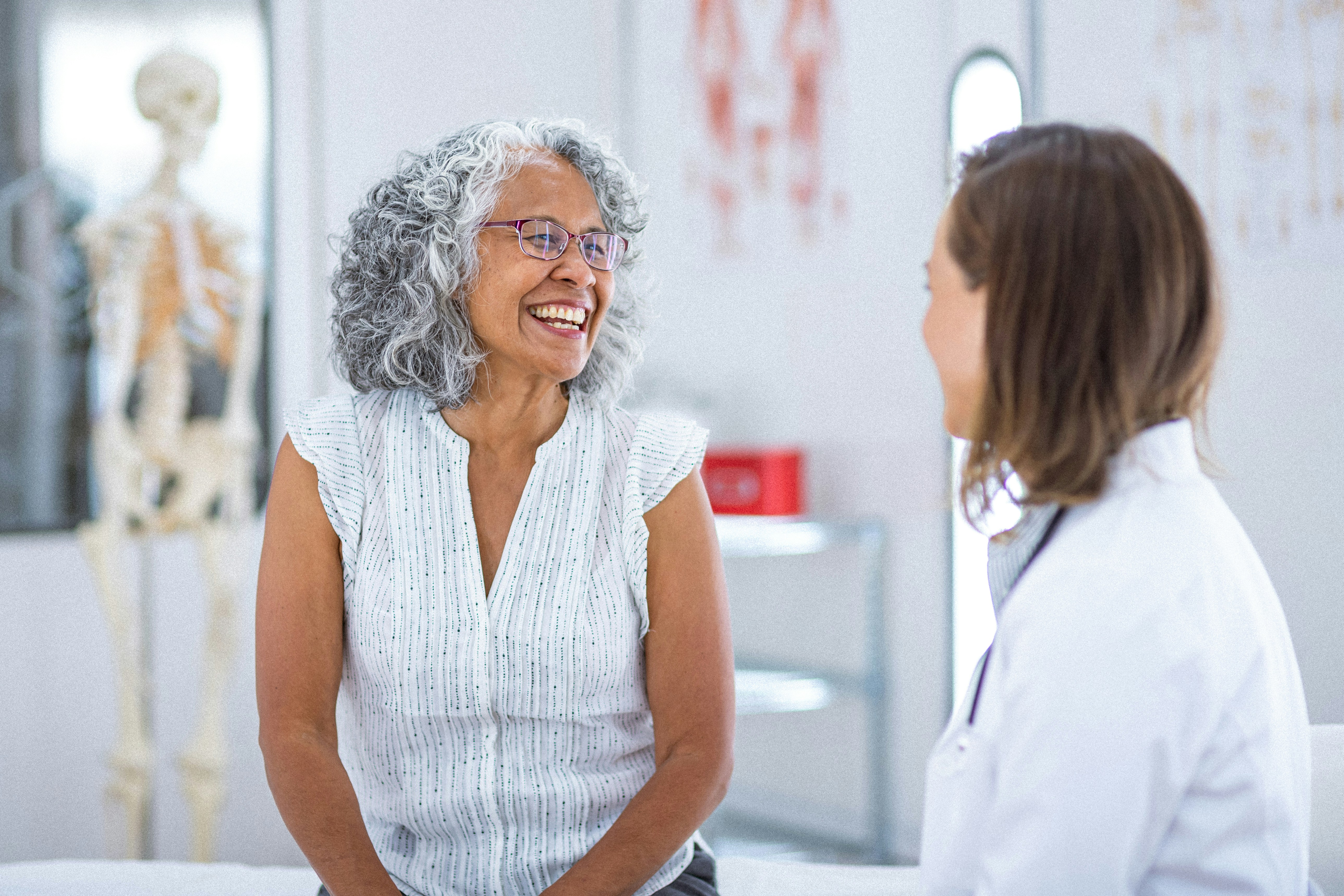 Hands stacked together with a healthcare provider in the background.
