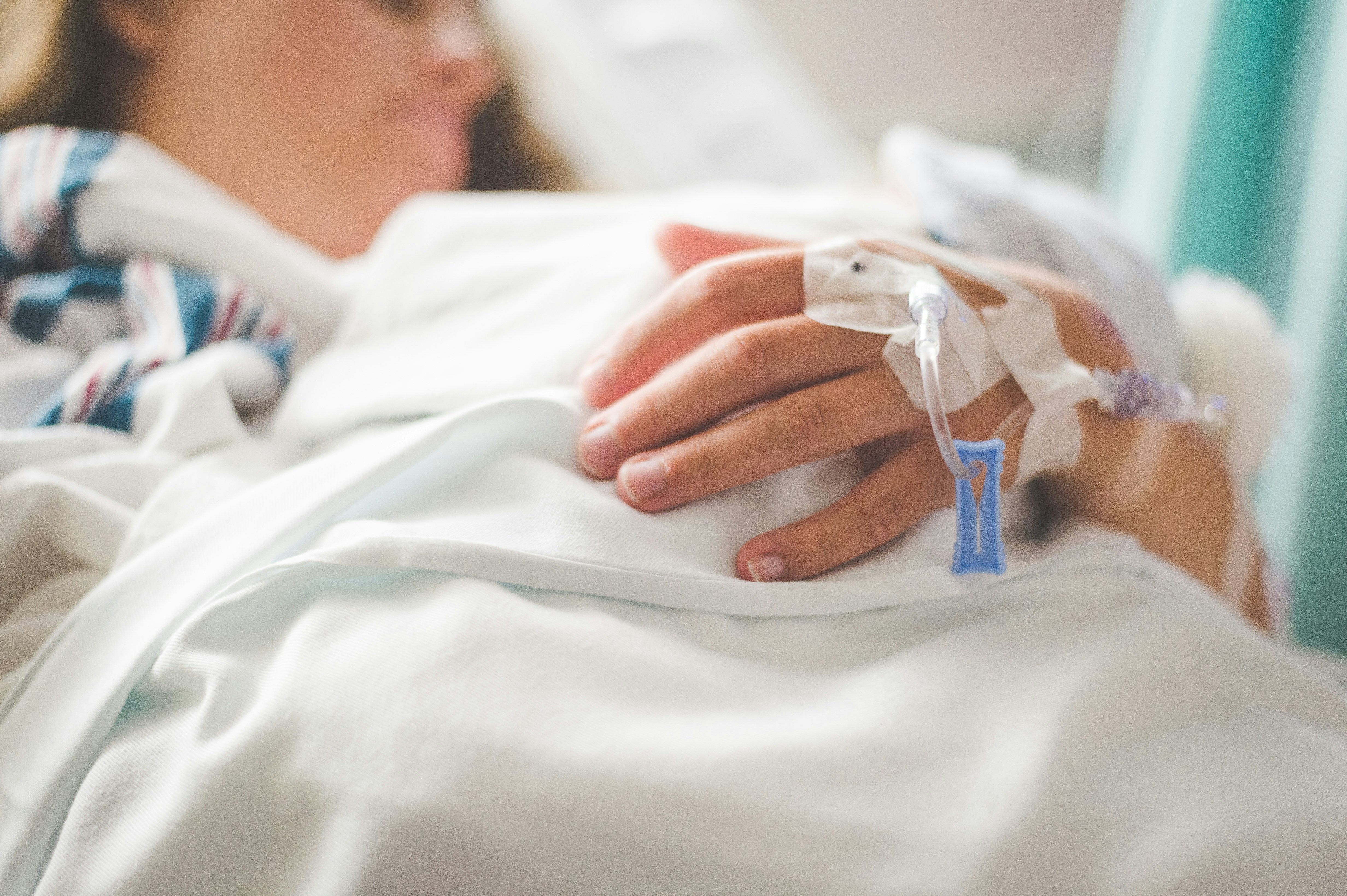 Hands stacked together with a healthcare provider in the background.
