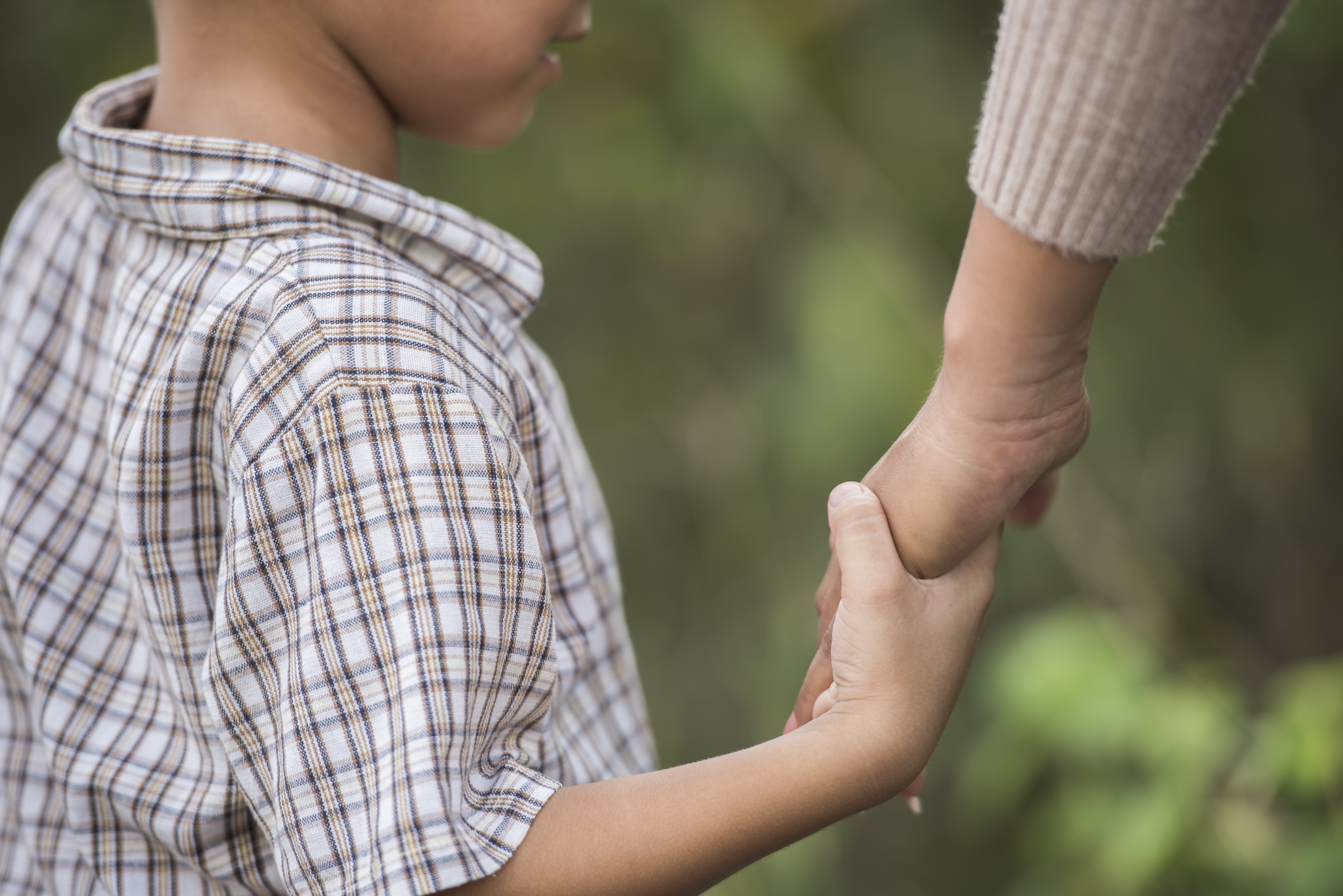 Child holding an adult's hand outdoors
