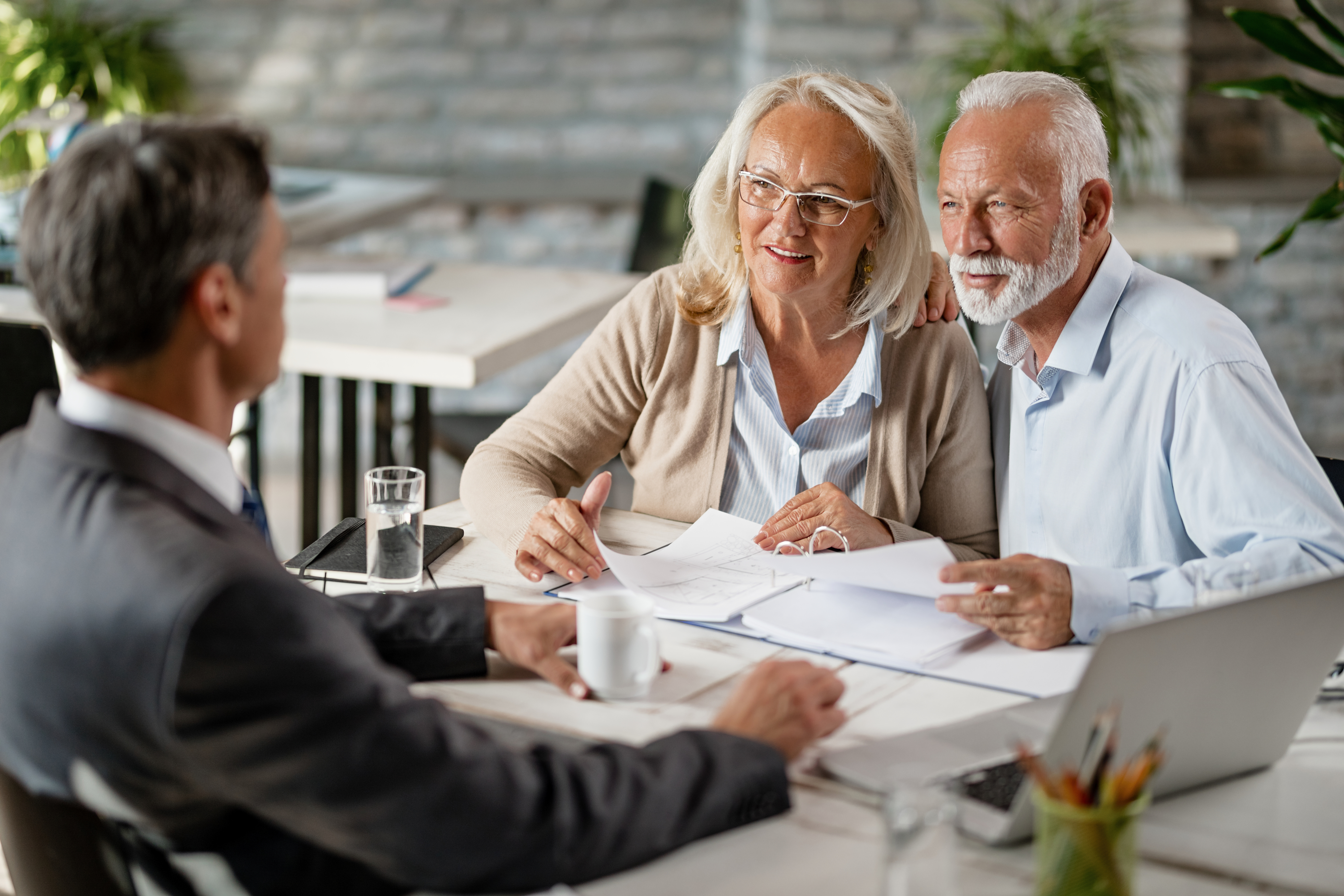 Elderly couple discussing documents with a professional in an office setting