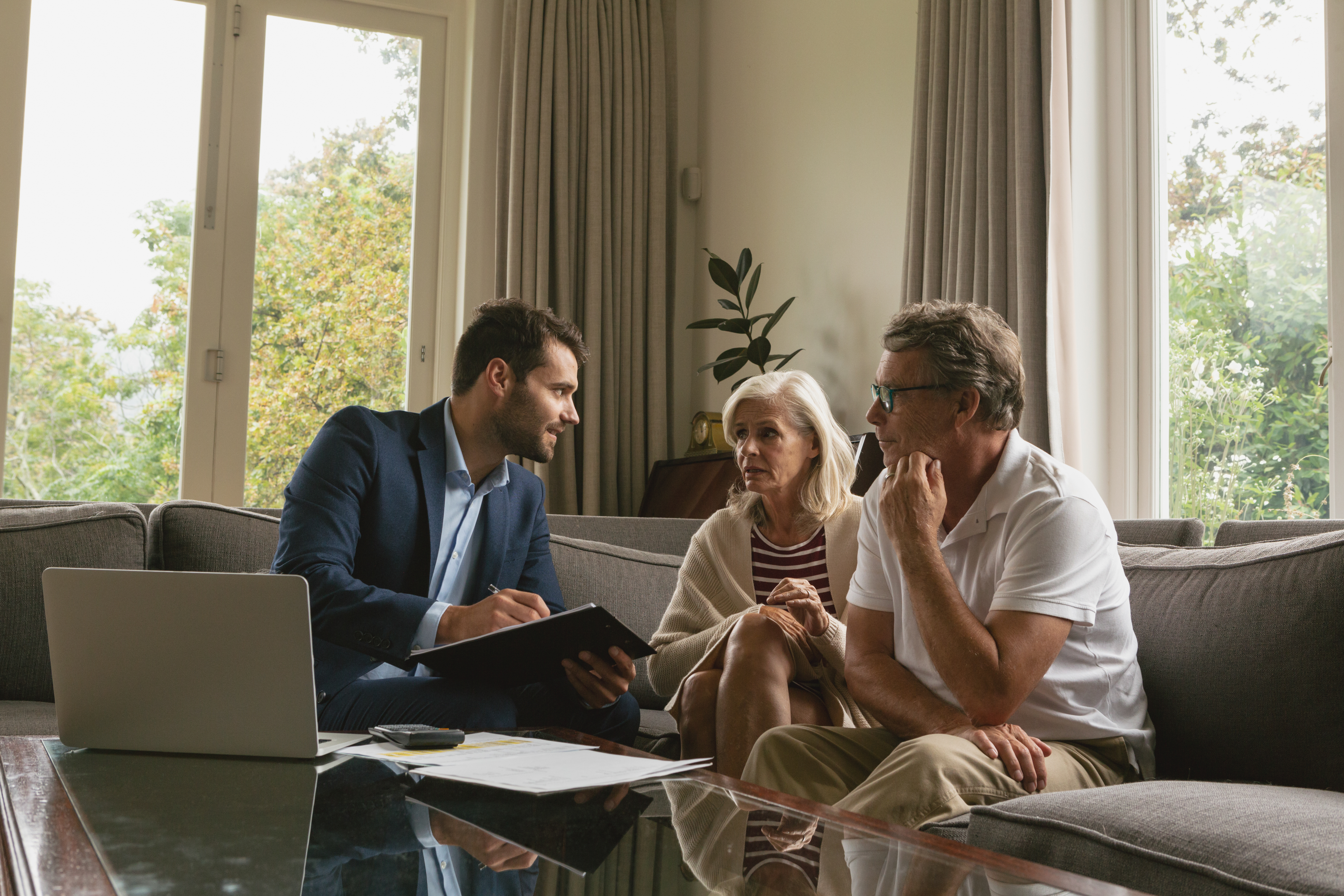 Financial advisor discussing estate planning with an elderly couple in a living room.