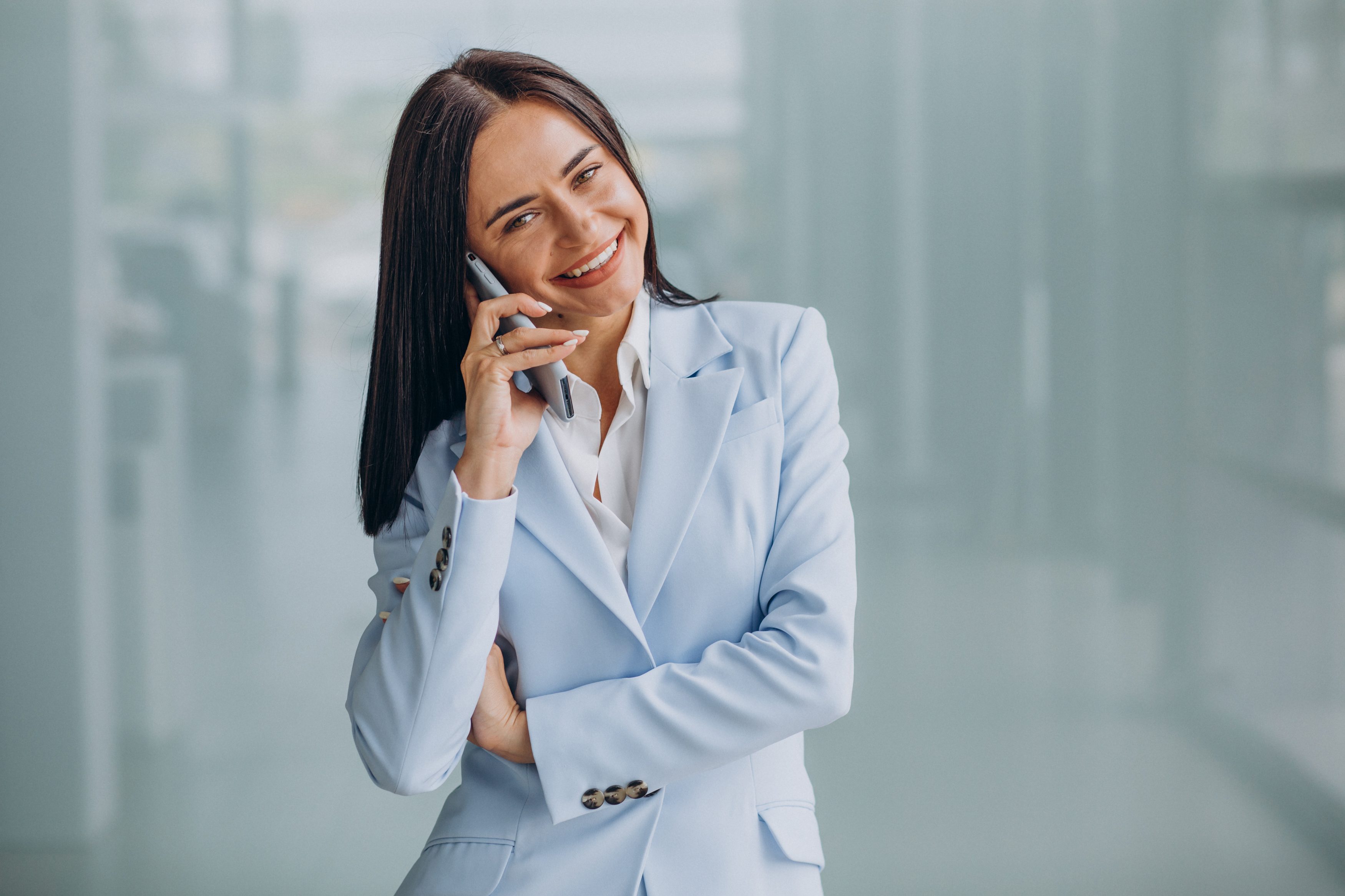 Businesswoman in a light blue suit talking on a smartphone