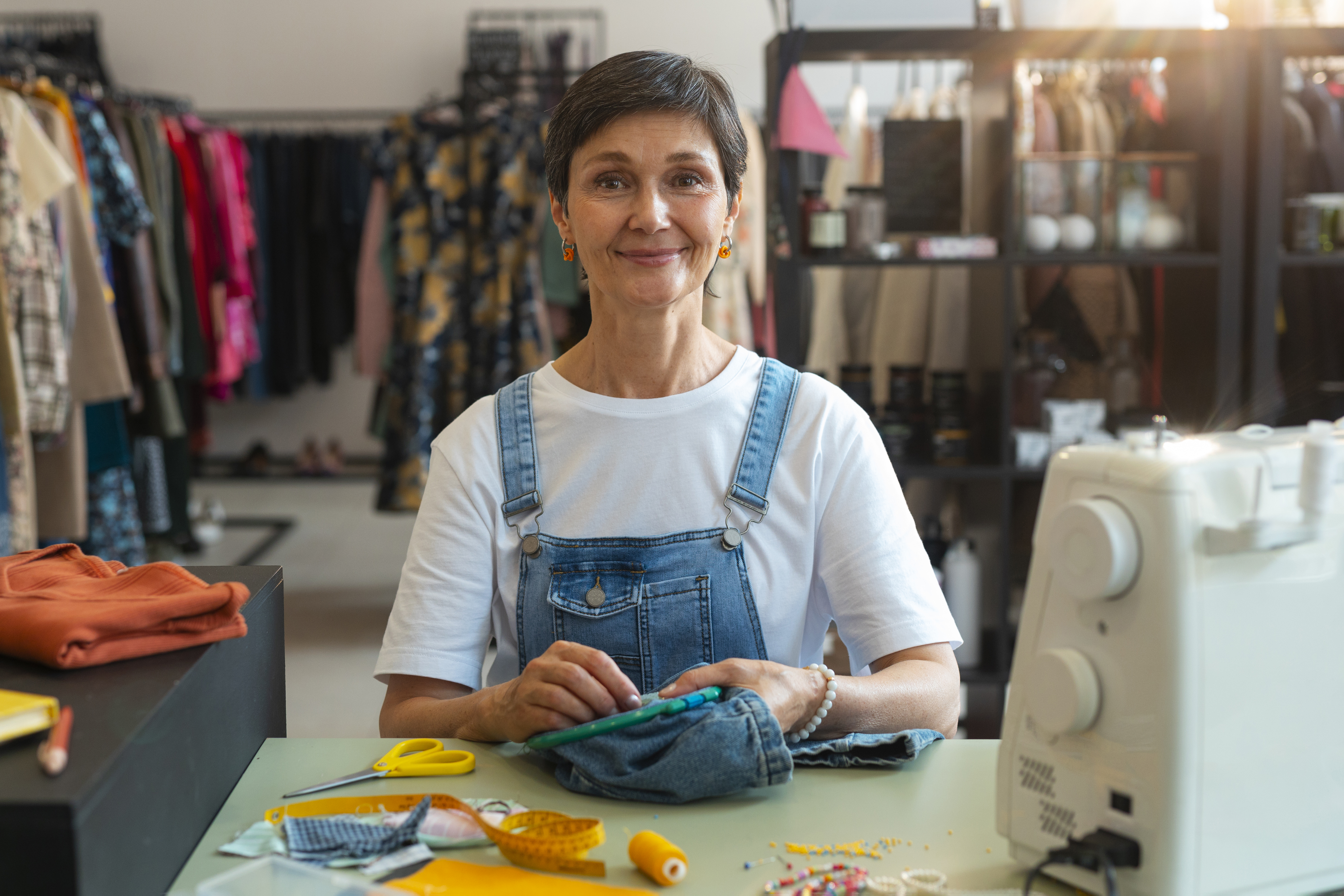 Smiling woman in a sewing workshop with sewing machine and fabric.