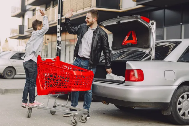 Father and son high-fiving next to a car with a shopping cart