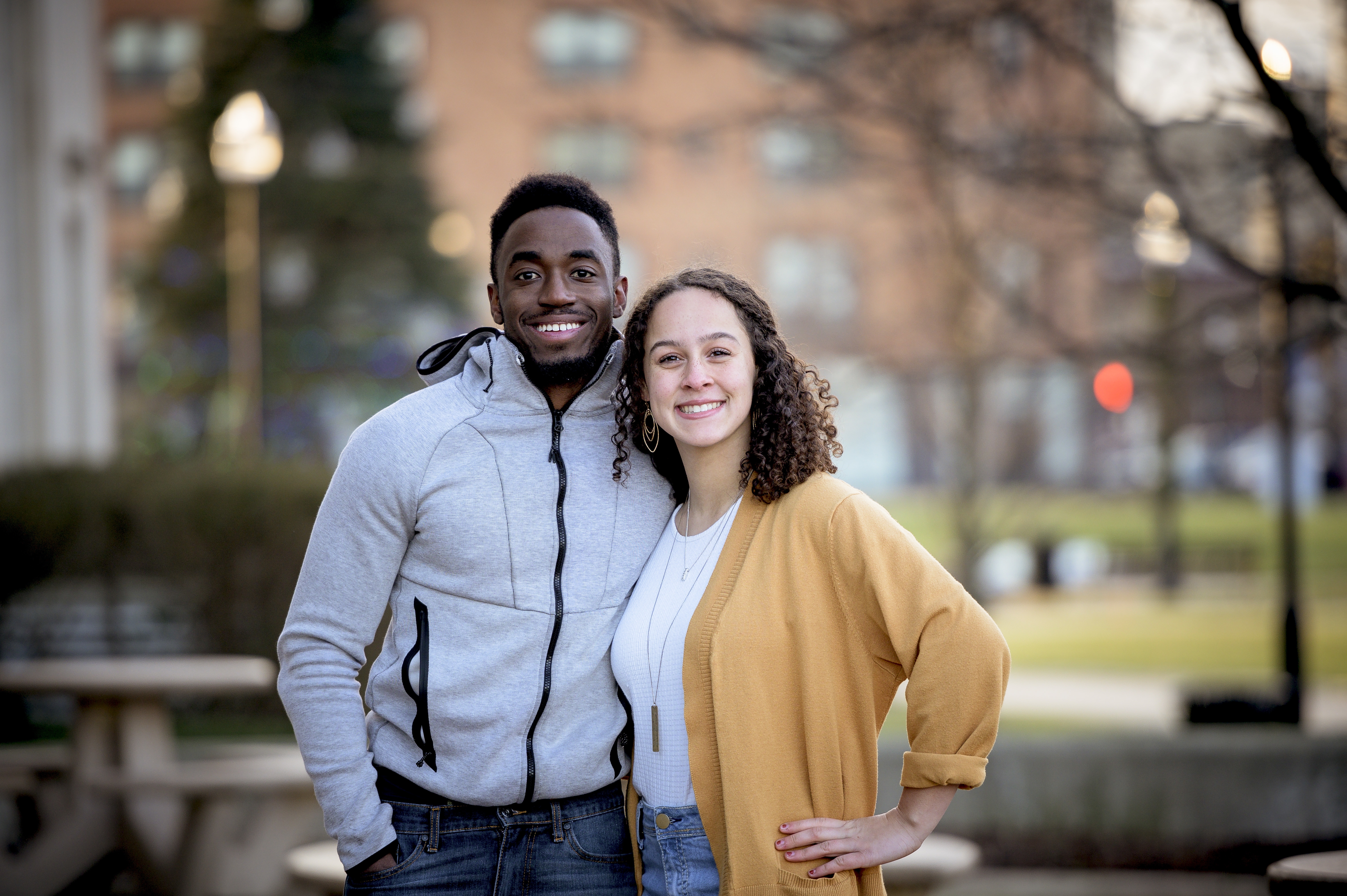 Two people smiling and standing together outdoors in a park setting