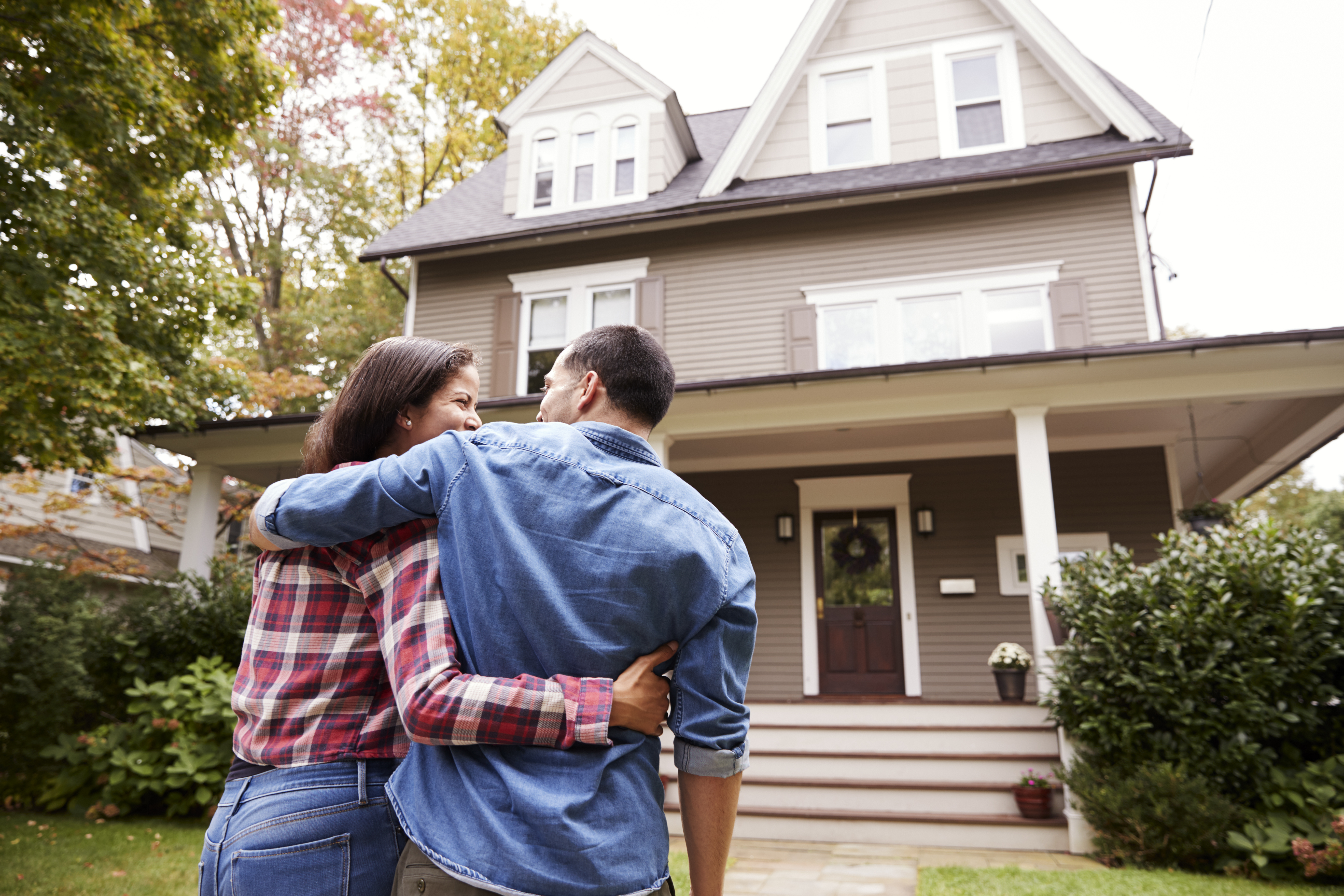 Couple embracing in front of their new home.