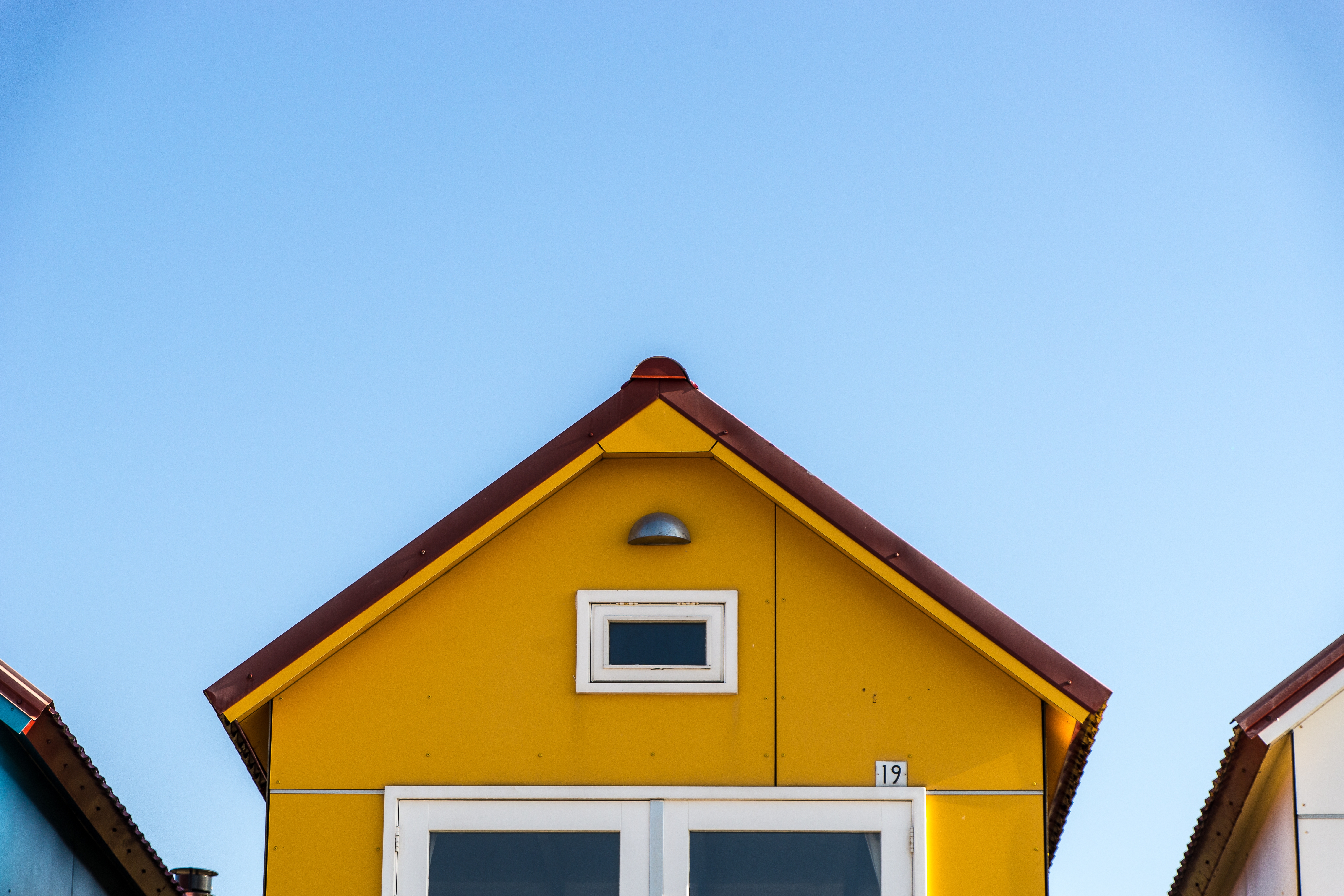 Yellow house with a triangular roof against a clear blue sky