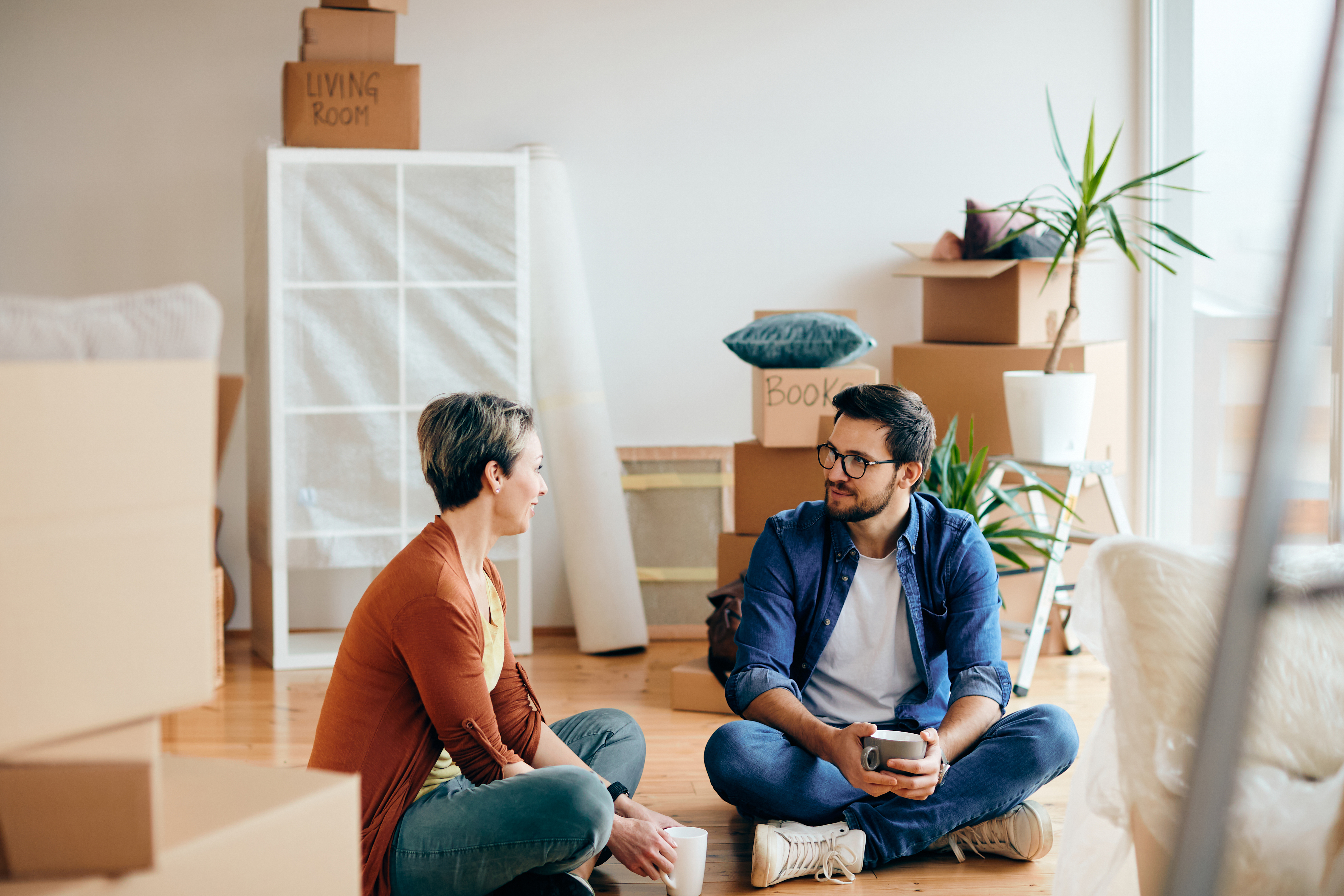 Couple sitting on the floor surrounded by moving boxes in a new home