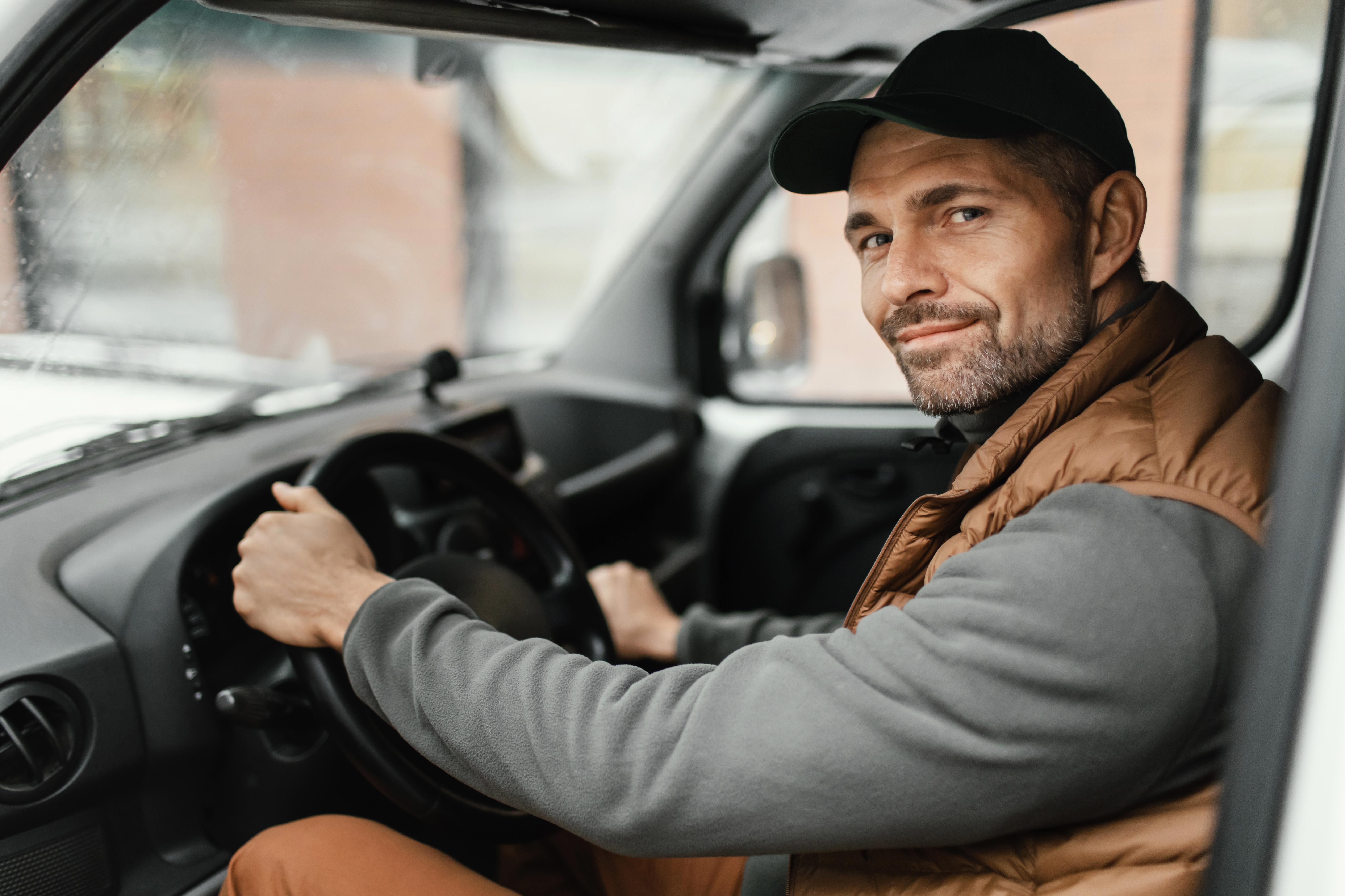Man in a cap driving a vehicle and looking at the camera