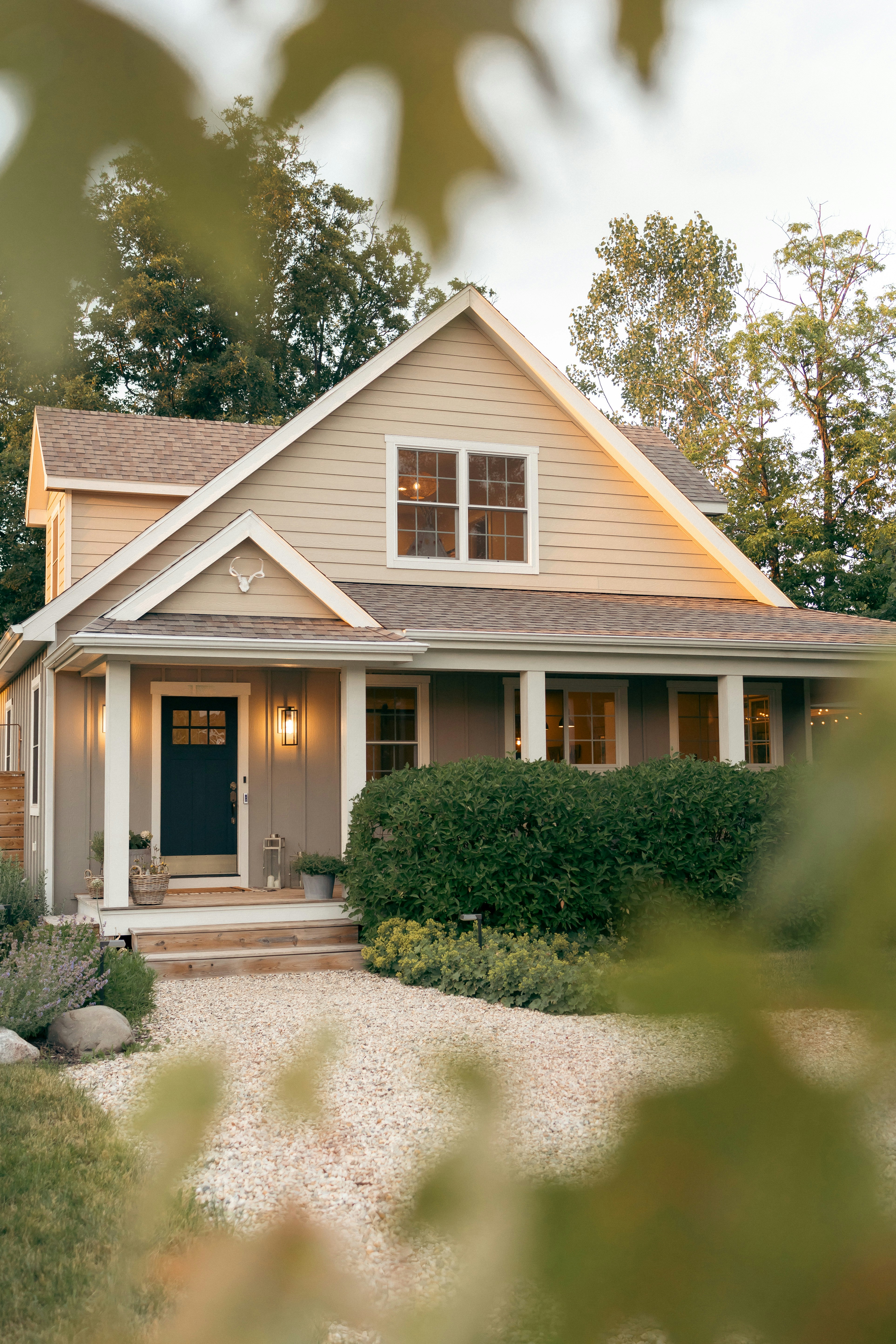 Gray shingle roof with a black vent near a brick wall and green trees in the background