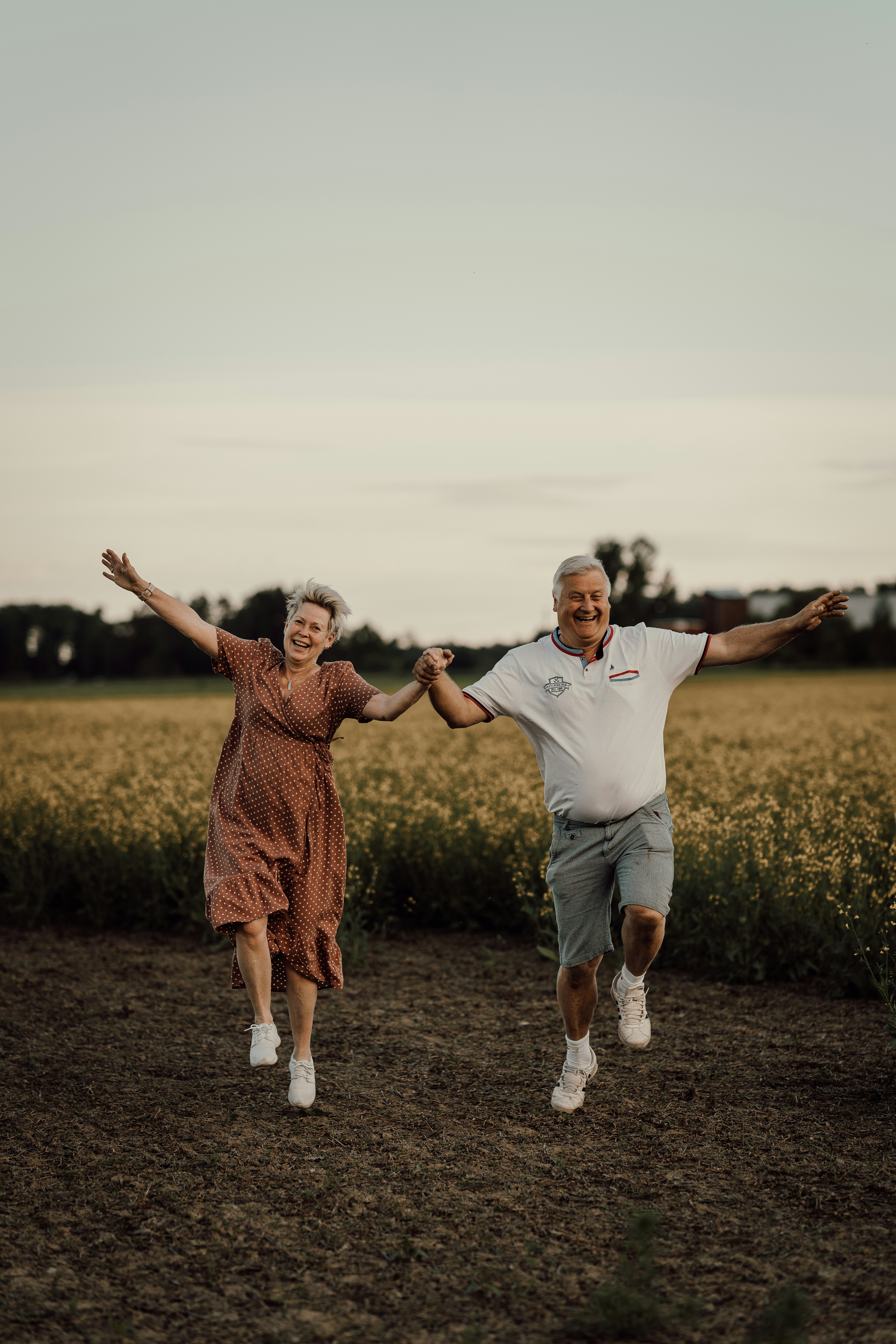 Elderly couple joyfully running through a field