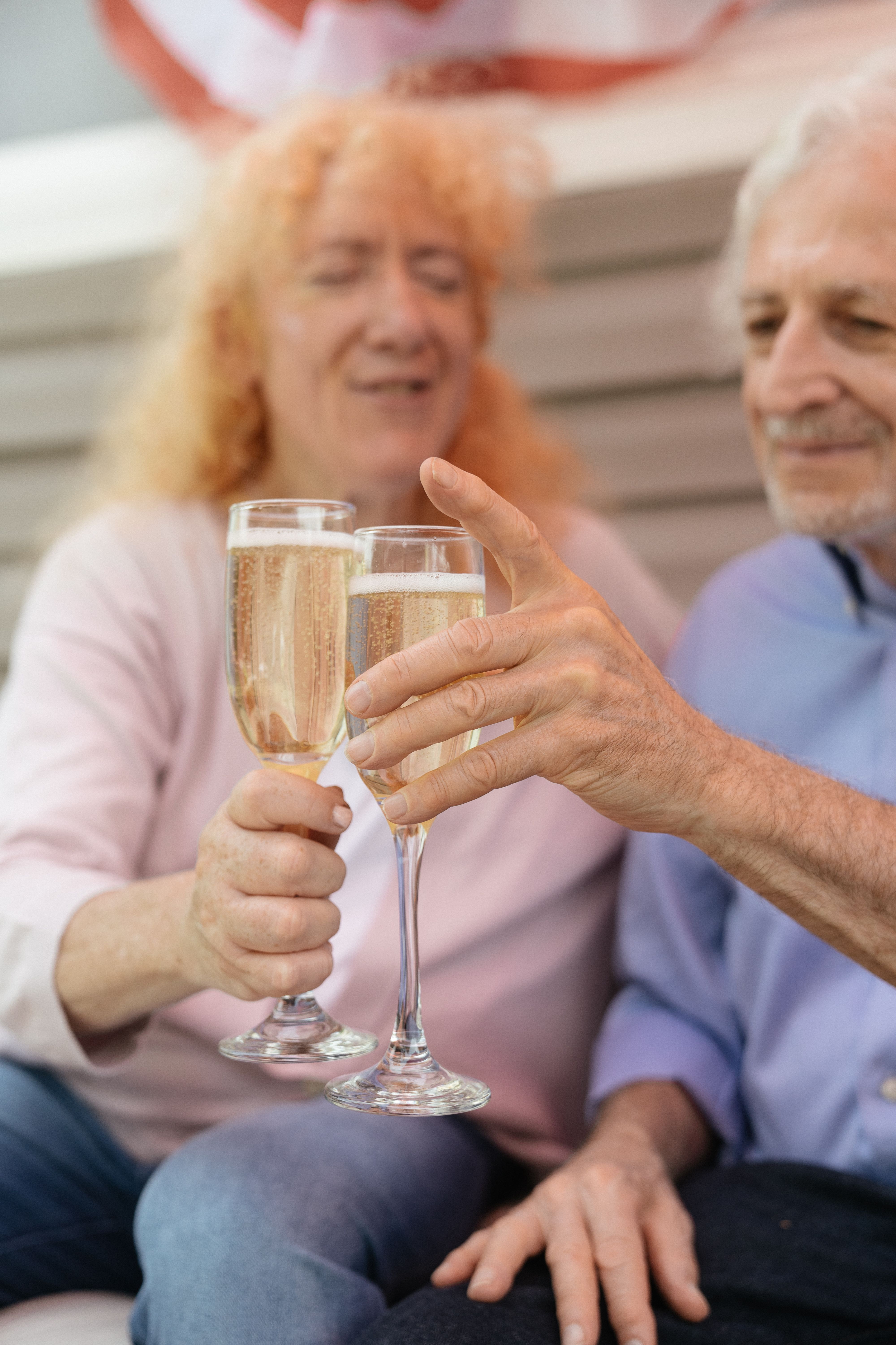 Two older adults clinking champagne glasses in a celebratory setting