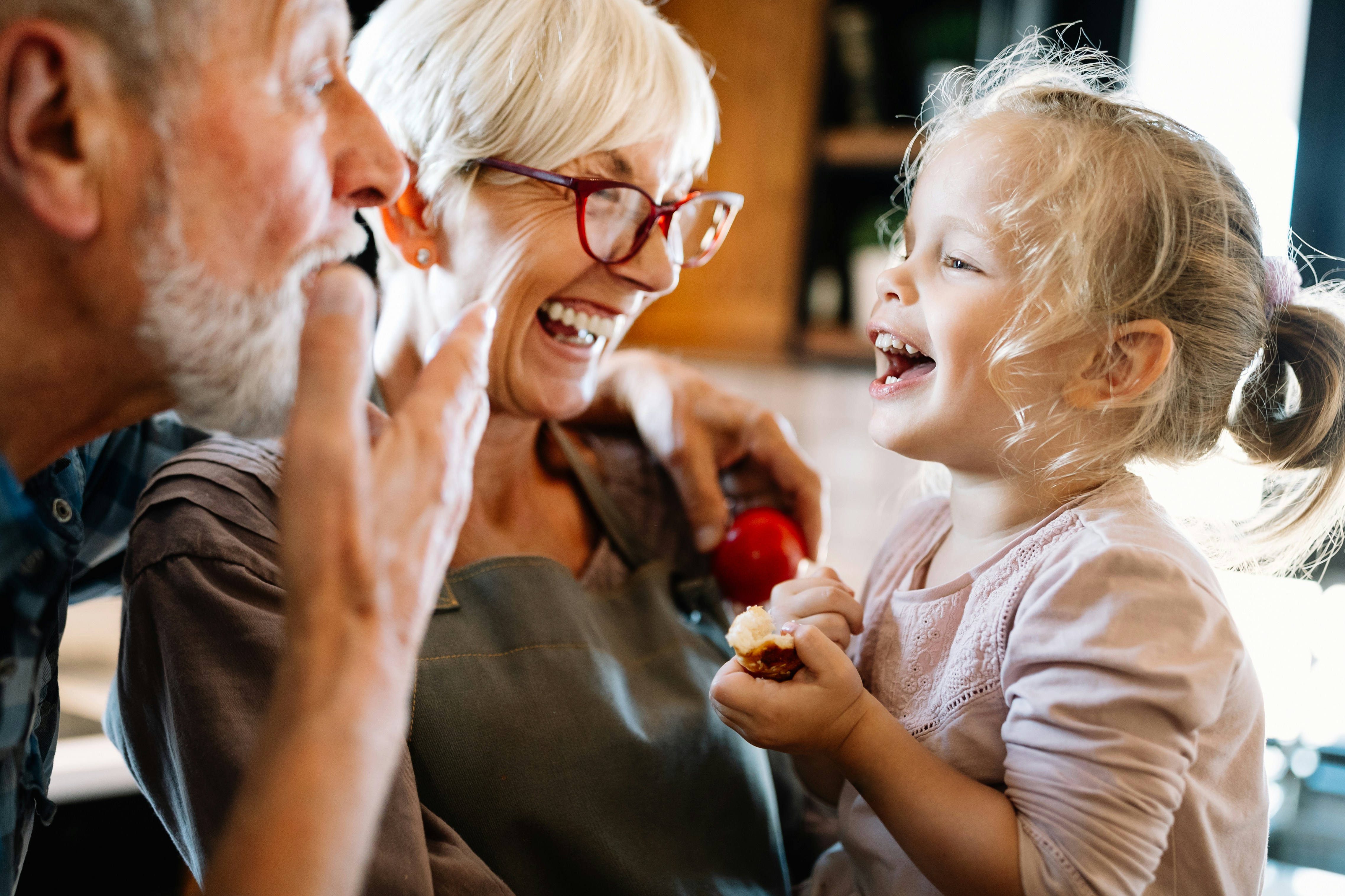Older couple laughing with a young girl in a kitchen setting